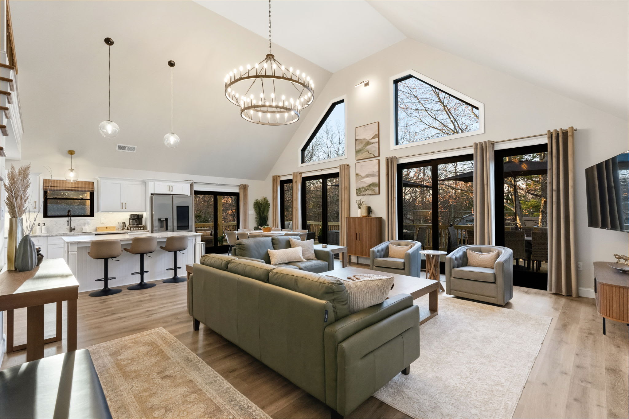 Open great room with vaulted ceilings, chandelier, and chef's kitchen island