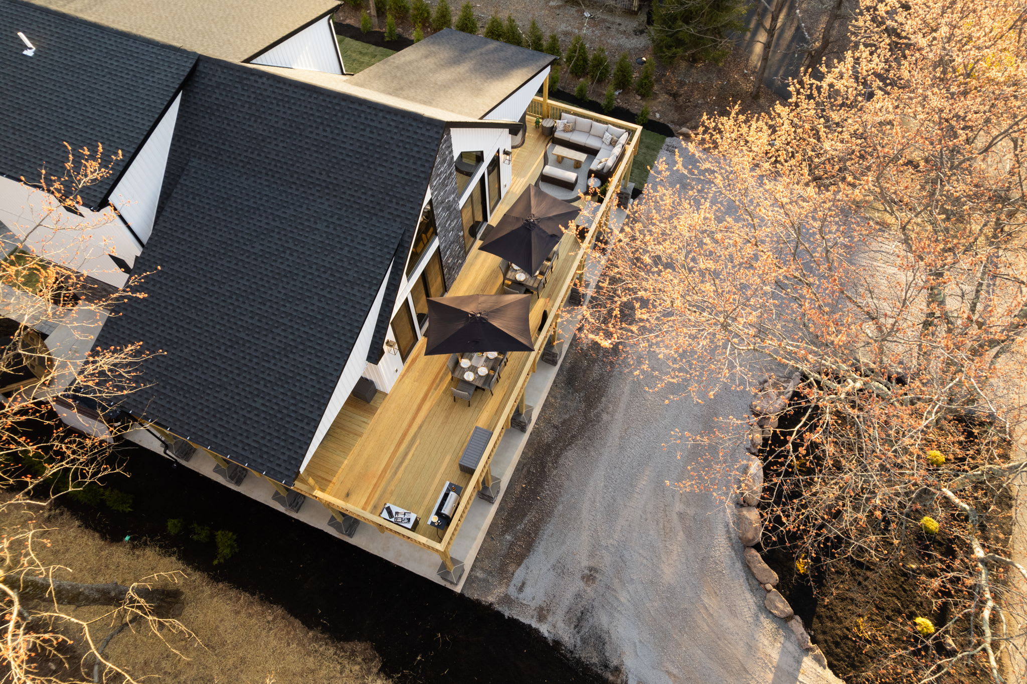 Top-down aerial of the expansive deck, pool, and wooded backyard