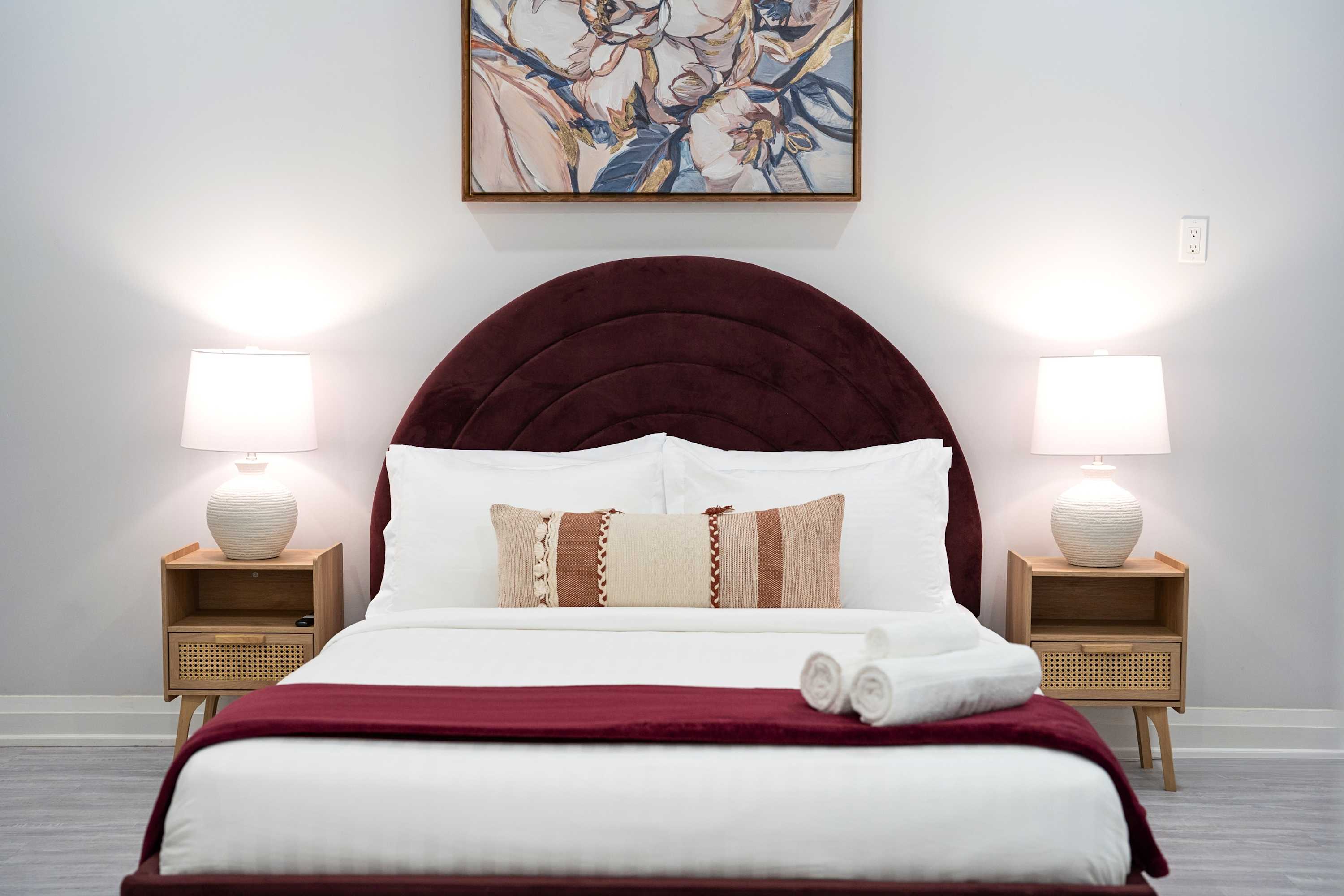 Queen bed with headboard, soft lighting, and fresh linens designed for a restful stay.