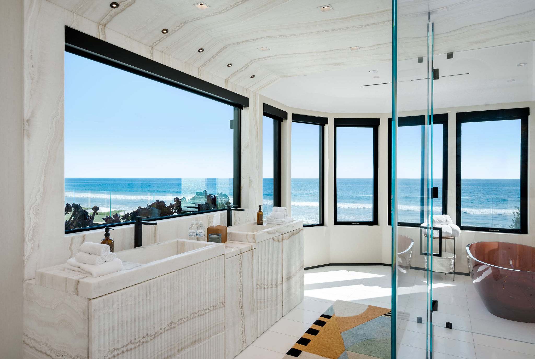 Soak with full-height glass opening to oceanfront views, with the bath set along the window line.