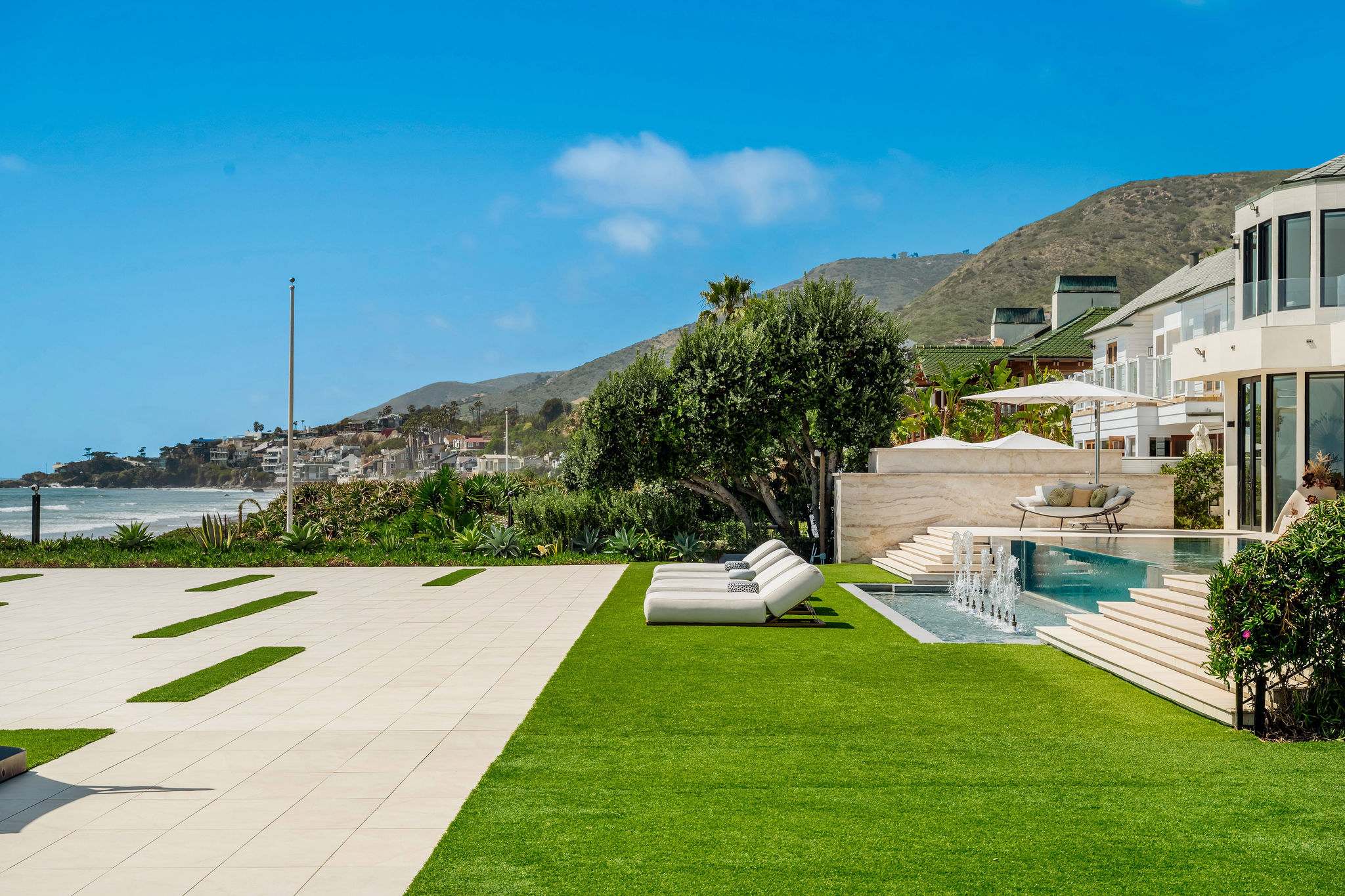 Move across the lawn toward the spa, with the coastline and hills surrounding you.