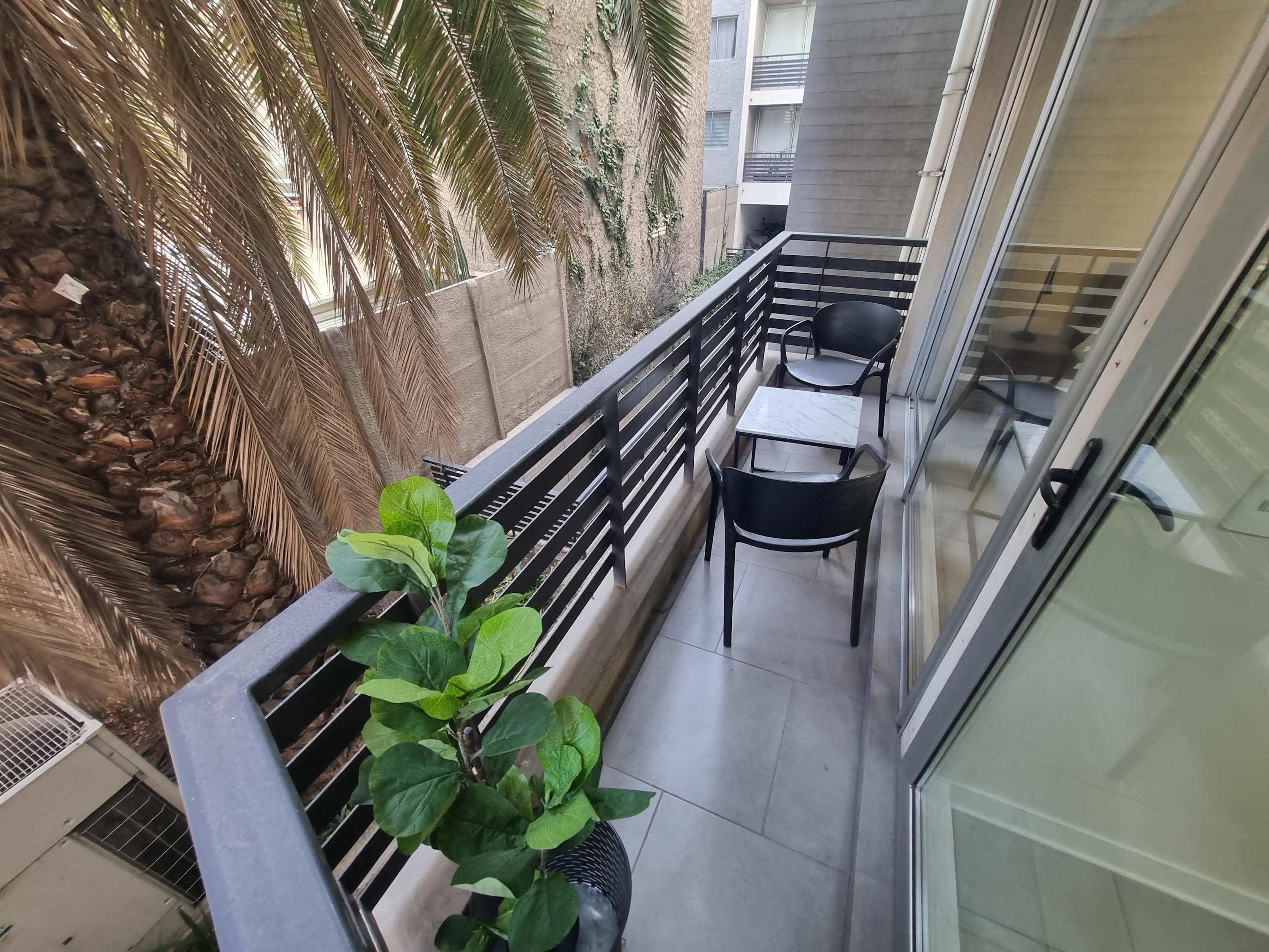 Cozy private balcony with seating and lush greenery, perfect for enjoying a morning coffee.