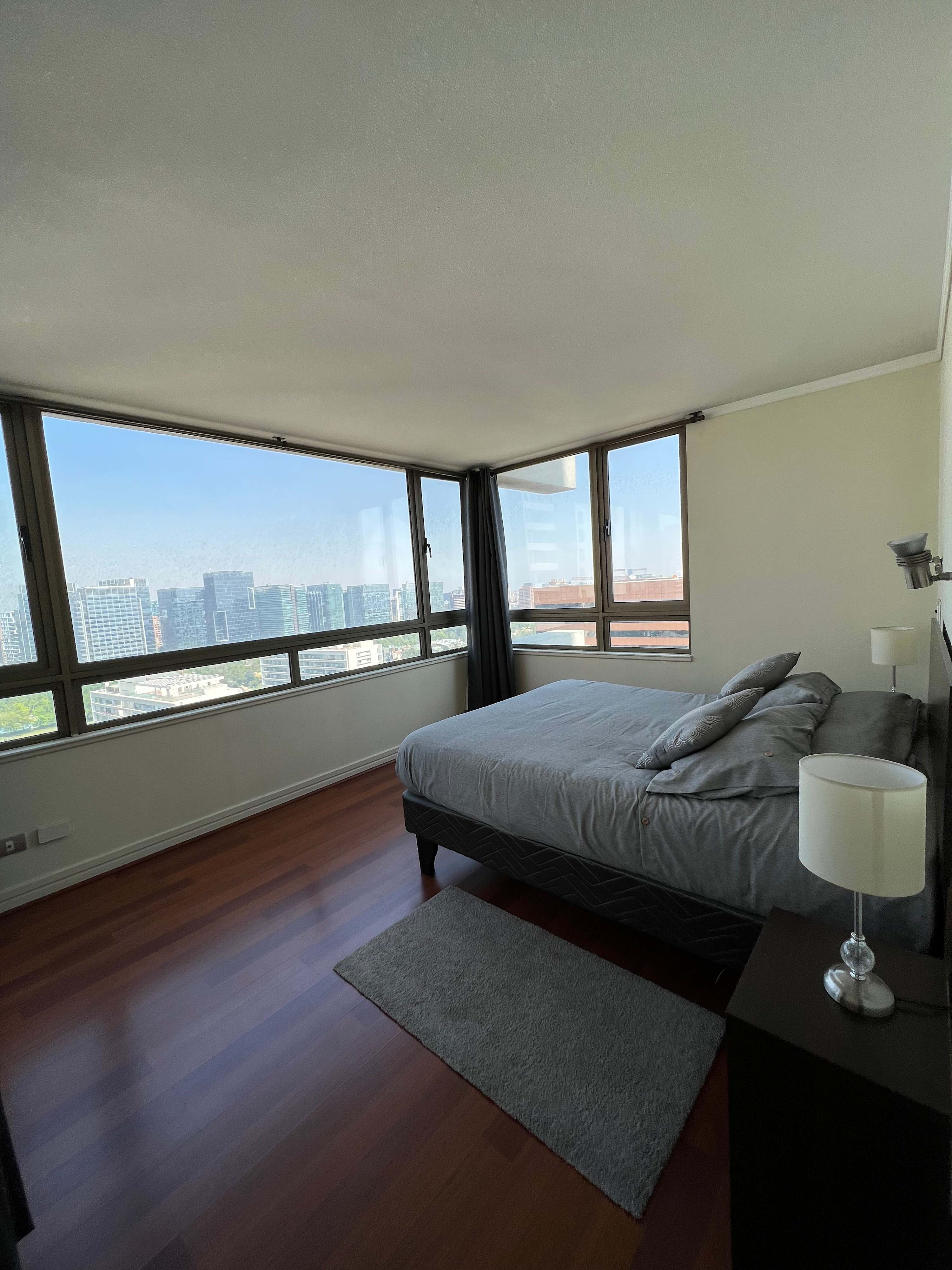 Relax in this bright bedroom with stunning city views and cozy gray bedding, perfect for unwinding after a day of exploring.