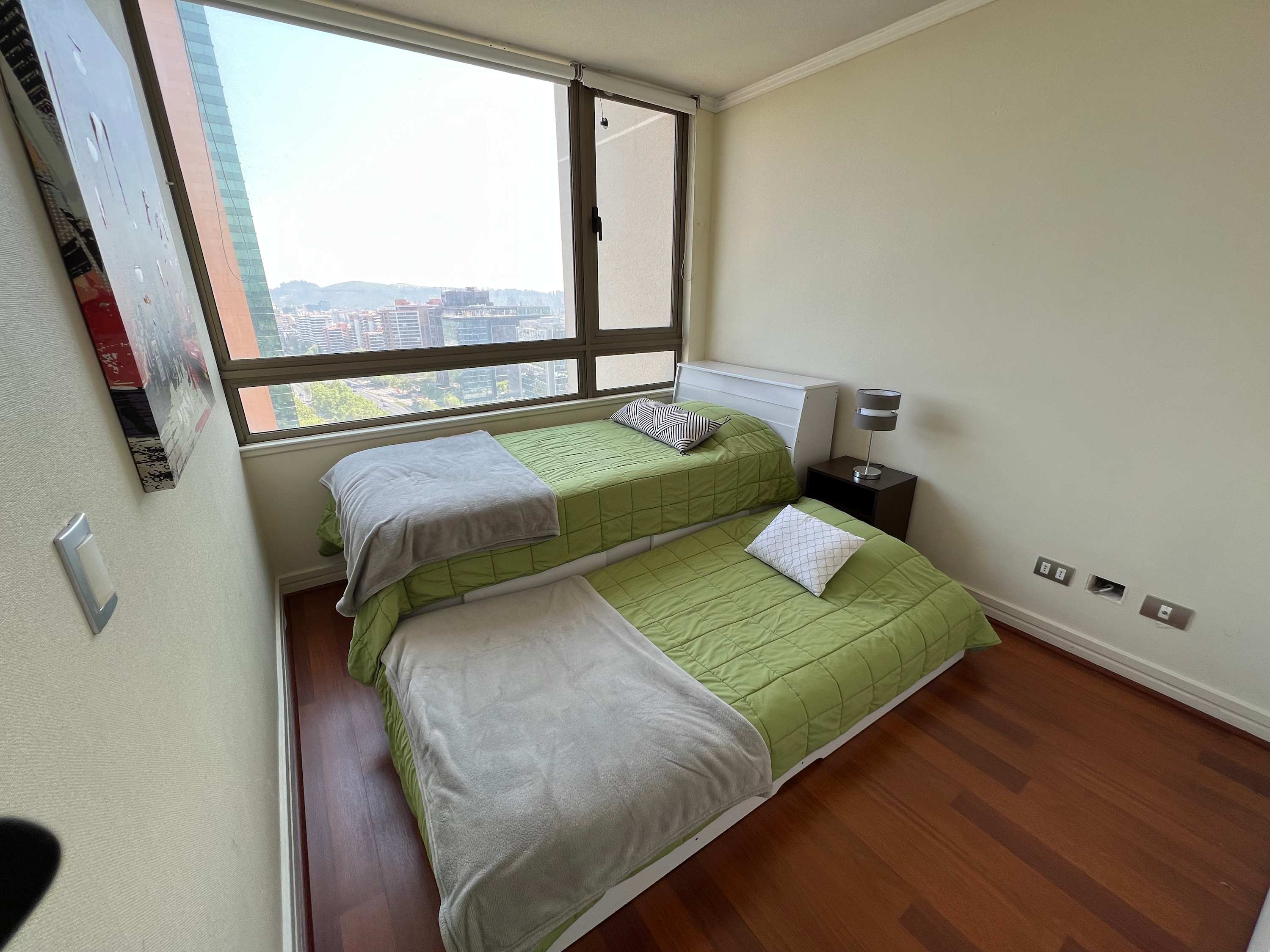 Cozy bedroom with twin beds and stunning city views, perfect for a restful stay.