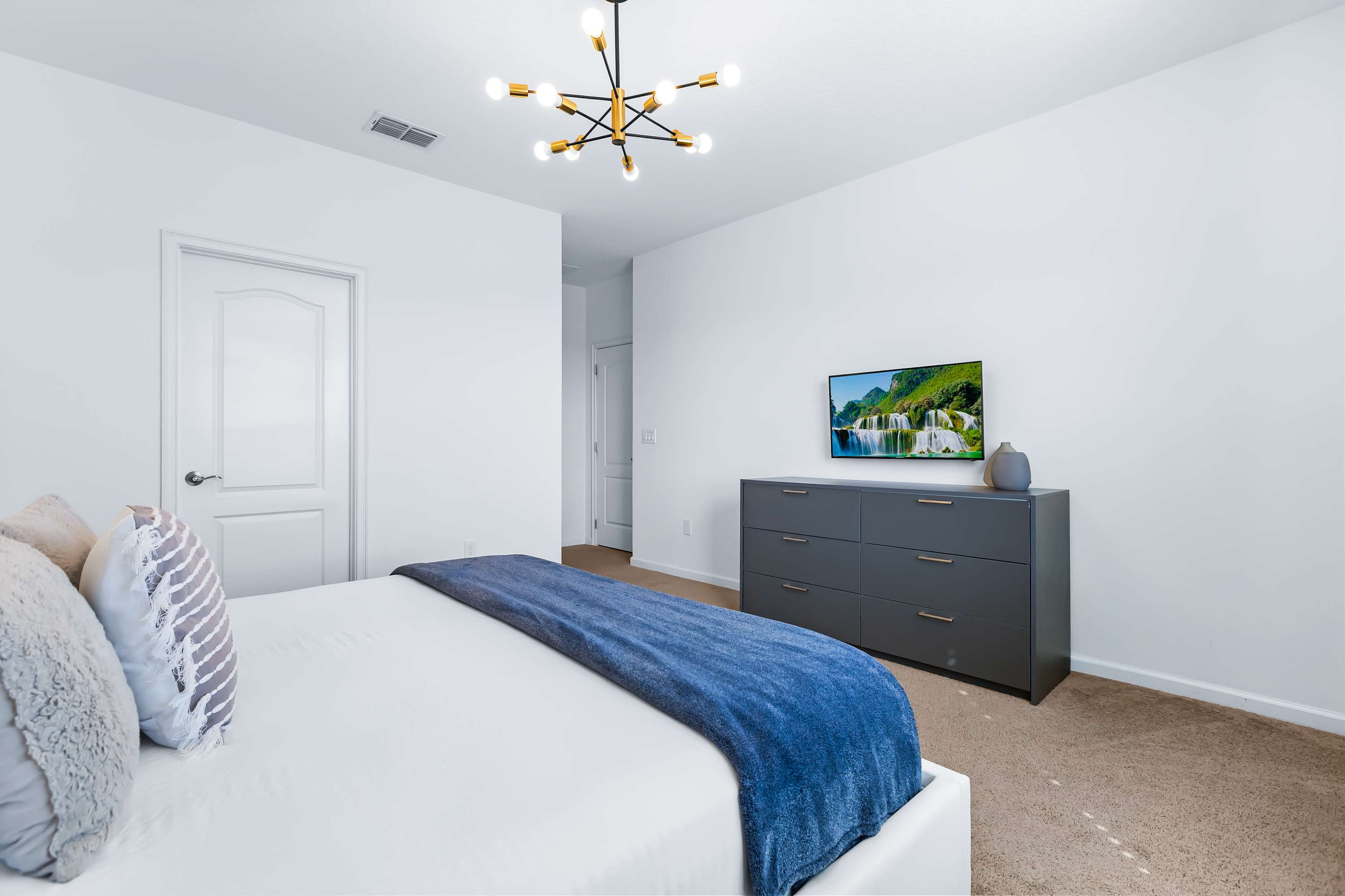 Primary bedroom with TV, cozy bedding, and minimalist design.