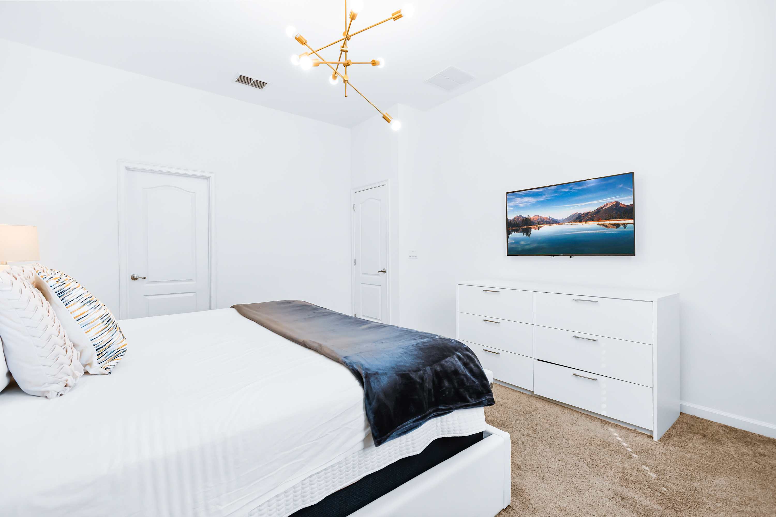 Bedroom with TV, cozy bedding, and minimalist design.