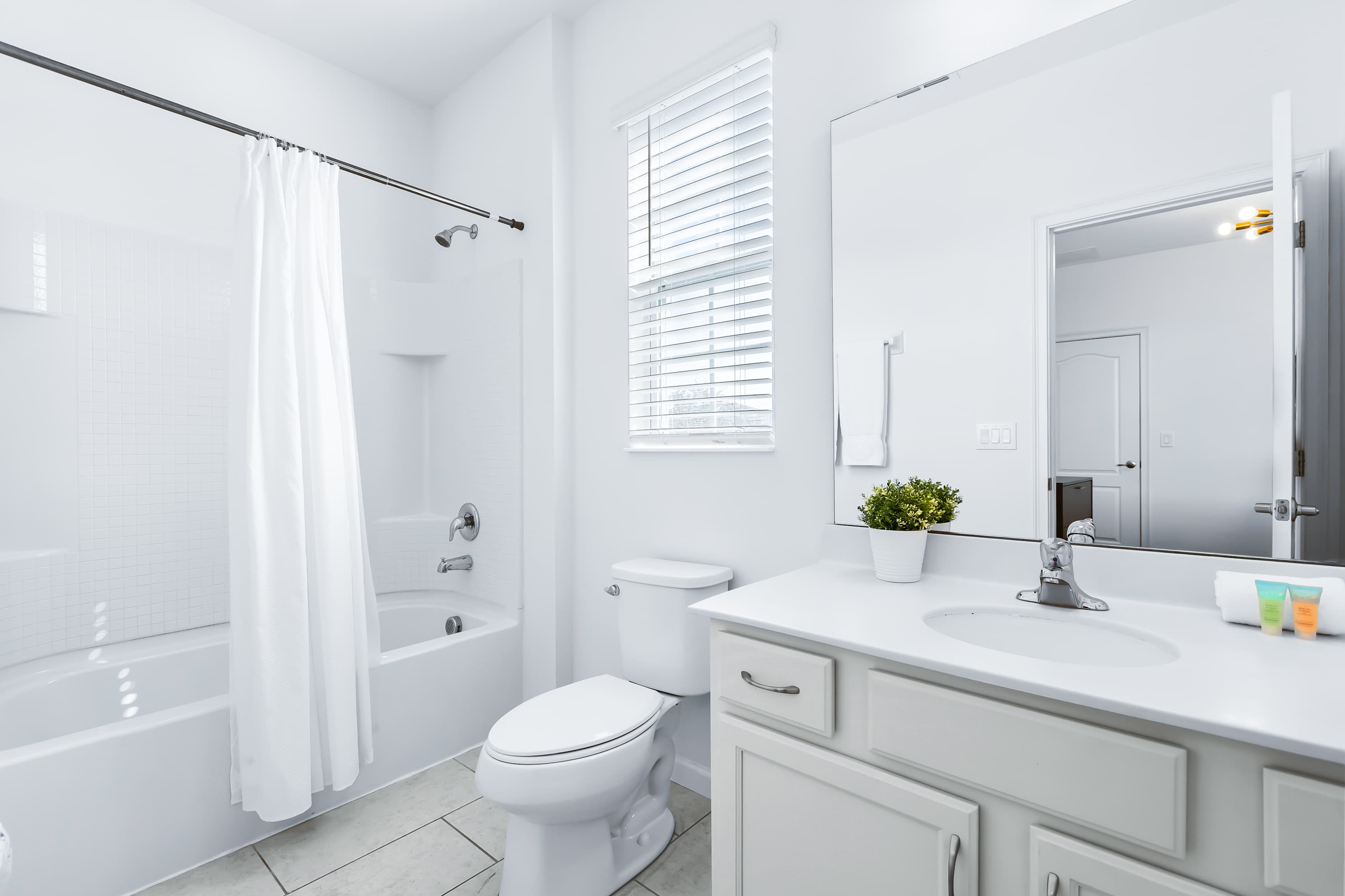 Bright bathroom with shower/tub combo and modern finishes.