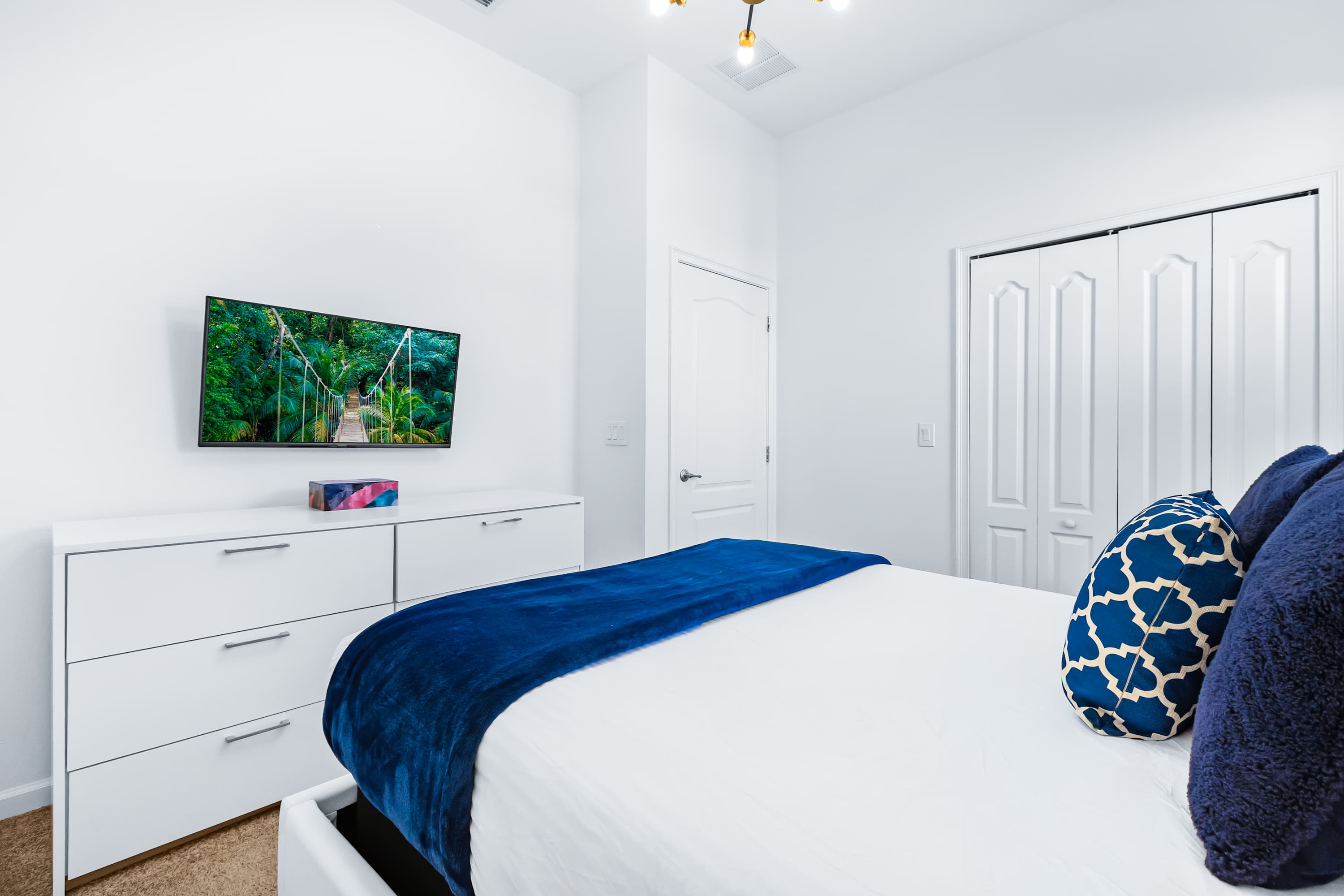 Bedroom with TV, cozy bedding, and minimalist design.