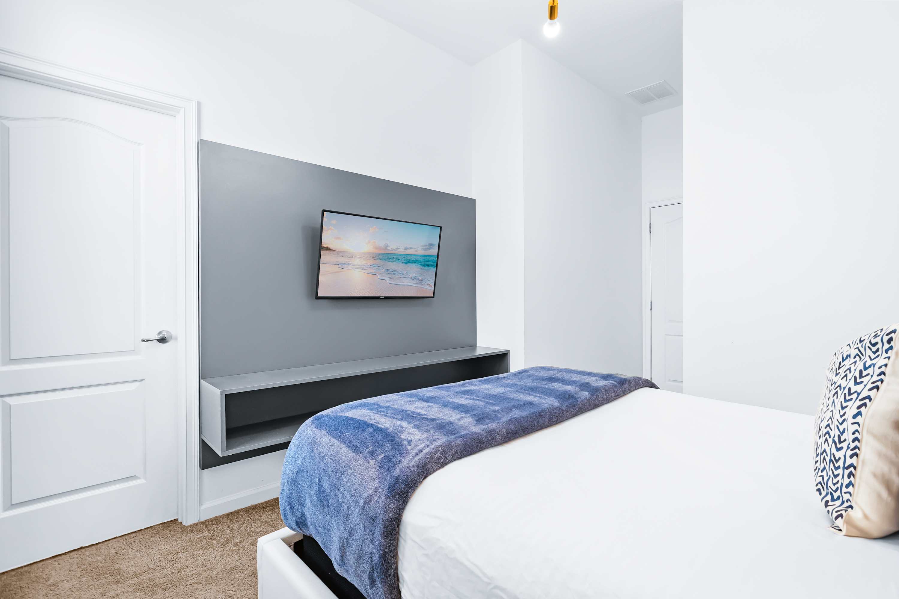 Bedroom with TV, cozy bedding, and minimalist design.