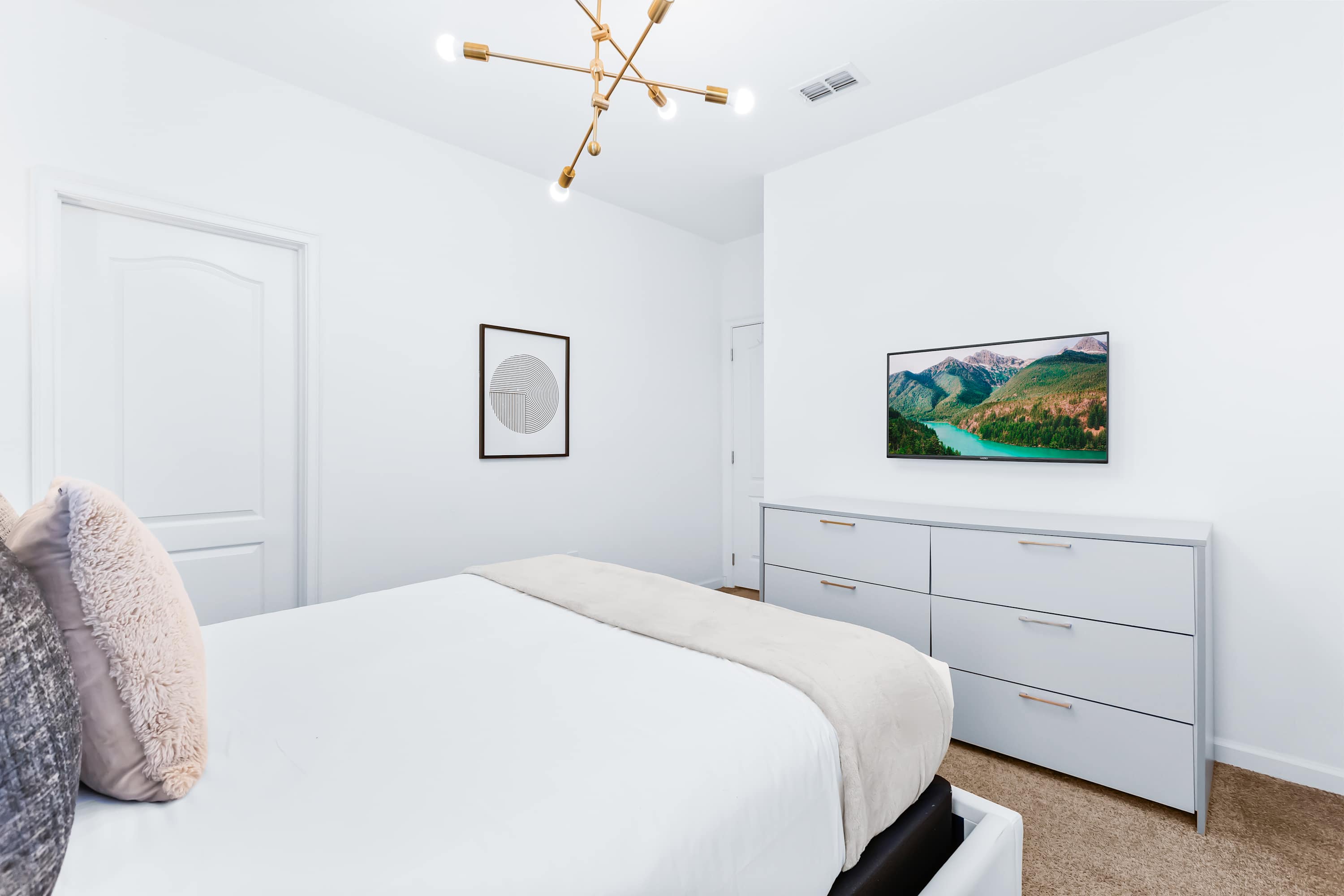 Bedroom with TV, cozy bedding, and minimalist design.