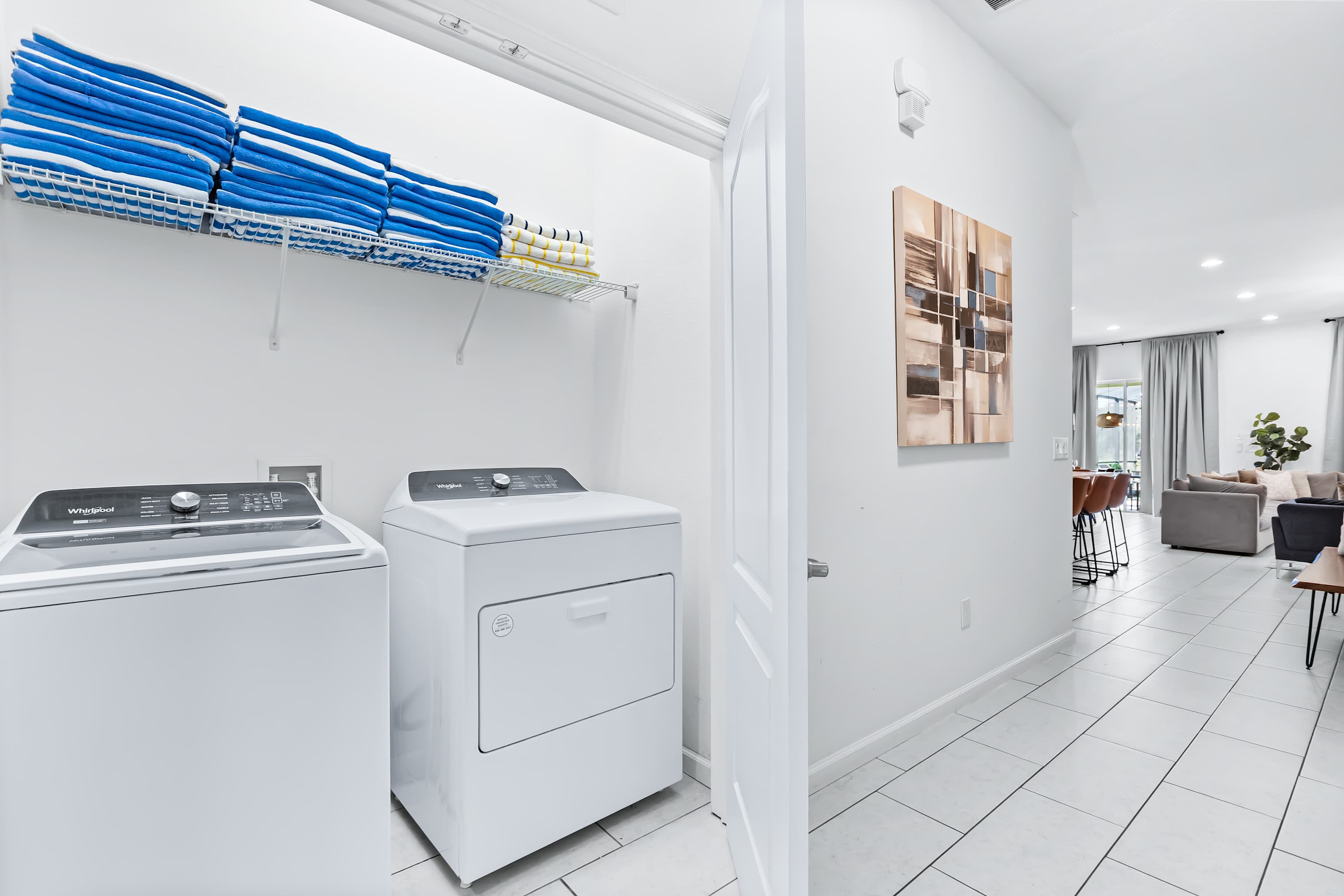 Laundry room with washer, dryer, and ample shelving.