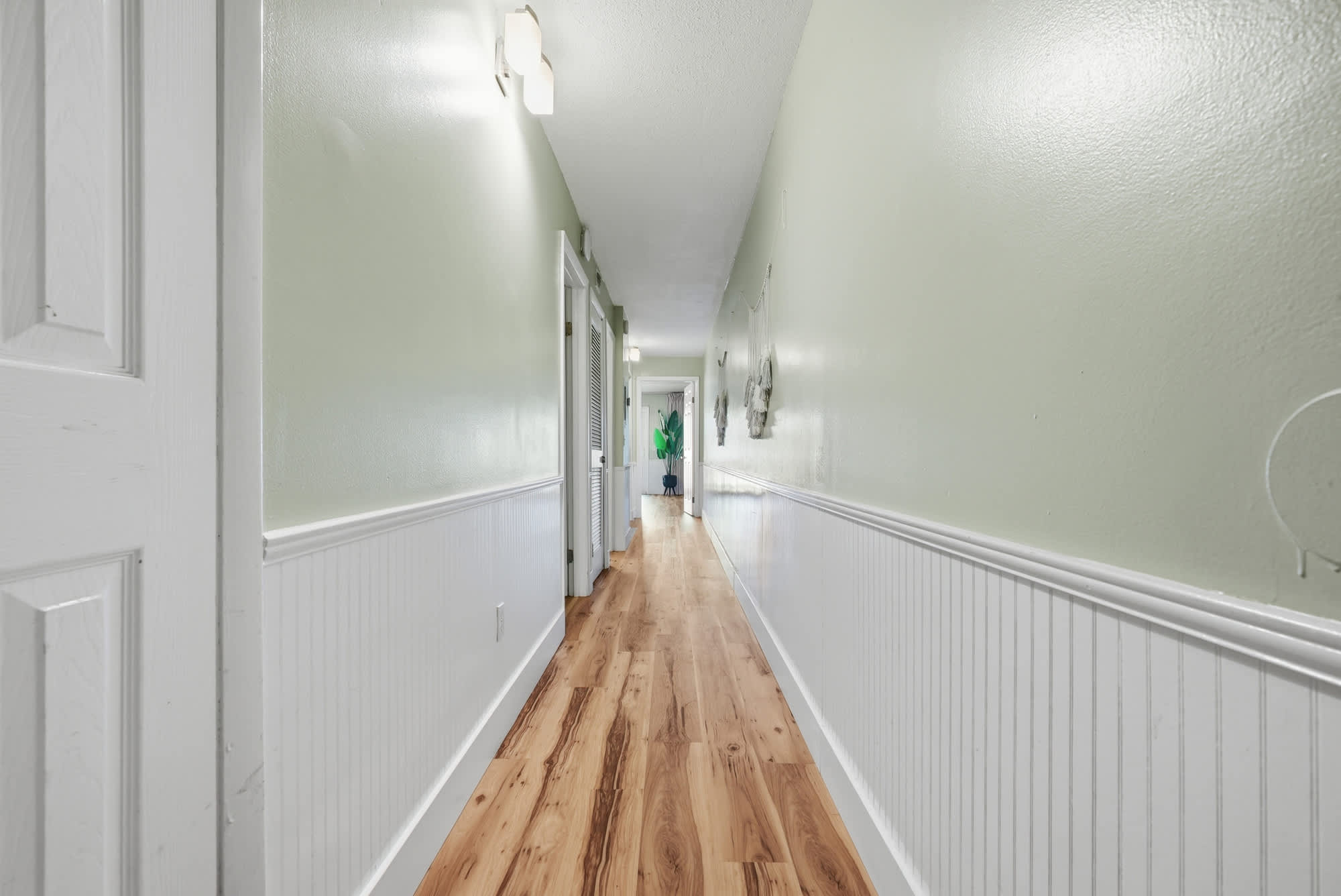The Summit 131 – Long hallway with light green walls, hardwood floors, and doors leading to adjoining rooms.