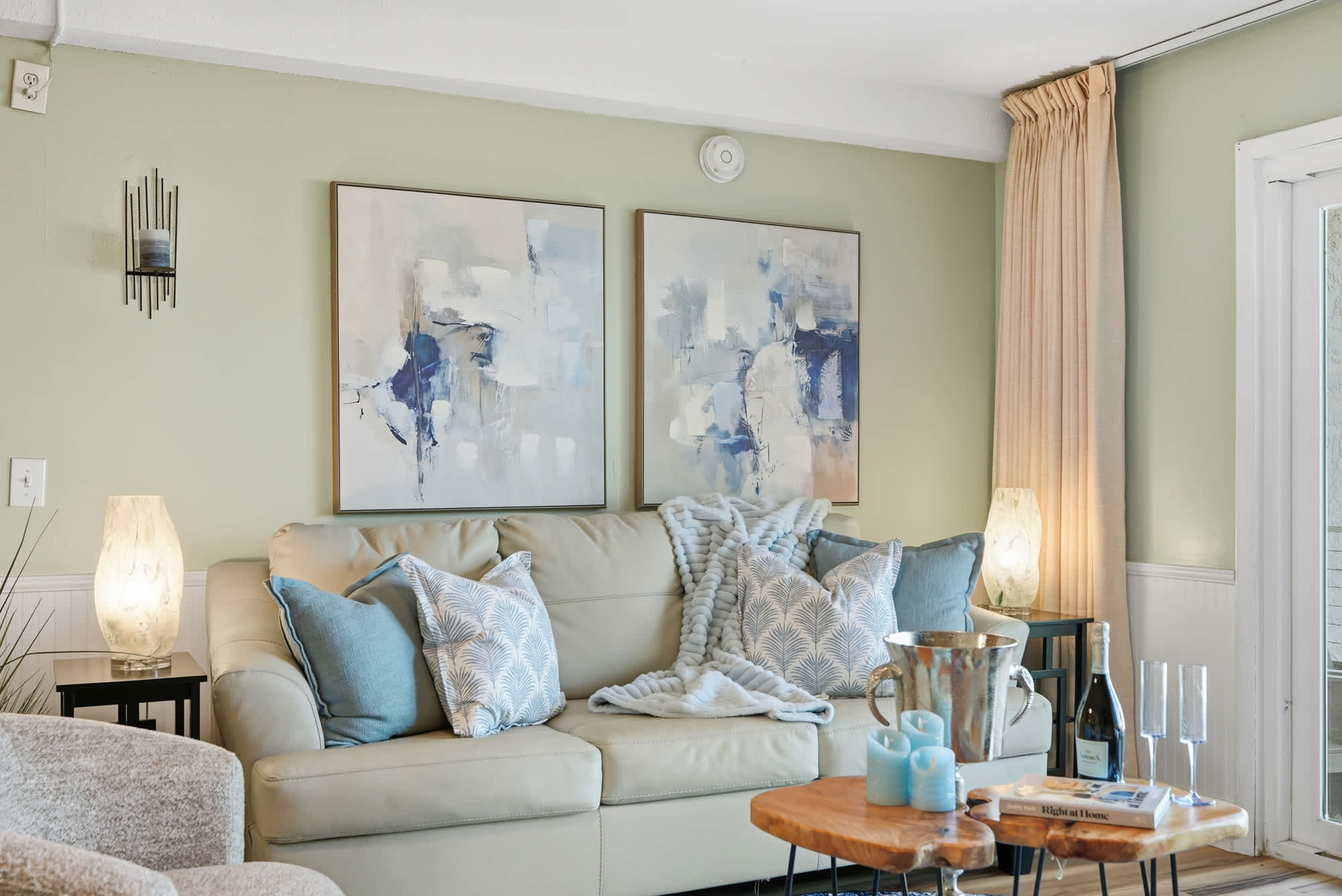 The Summit 131 – Cozy living room with a beige sofa, decorative pillows, modern artwork, and a small wooden coffee table.
