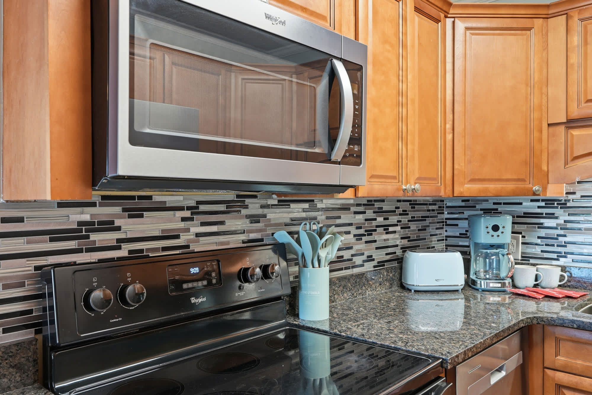 The Summit 131 – Modern kitchen with stainless steel appliances, granite countertops, and decorative tile backsplash.