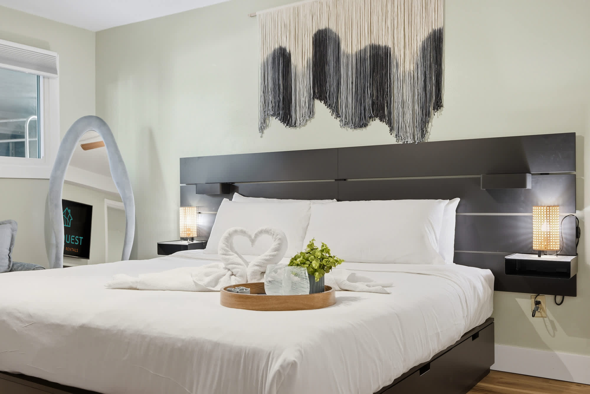 The Summit 131 – Modern bedroom with a king-sized bed, decorative wall hanging, and a TV visible in the corner.