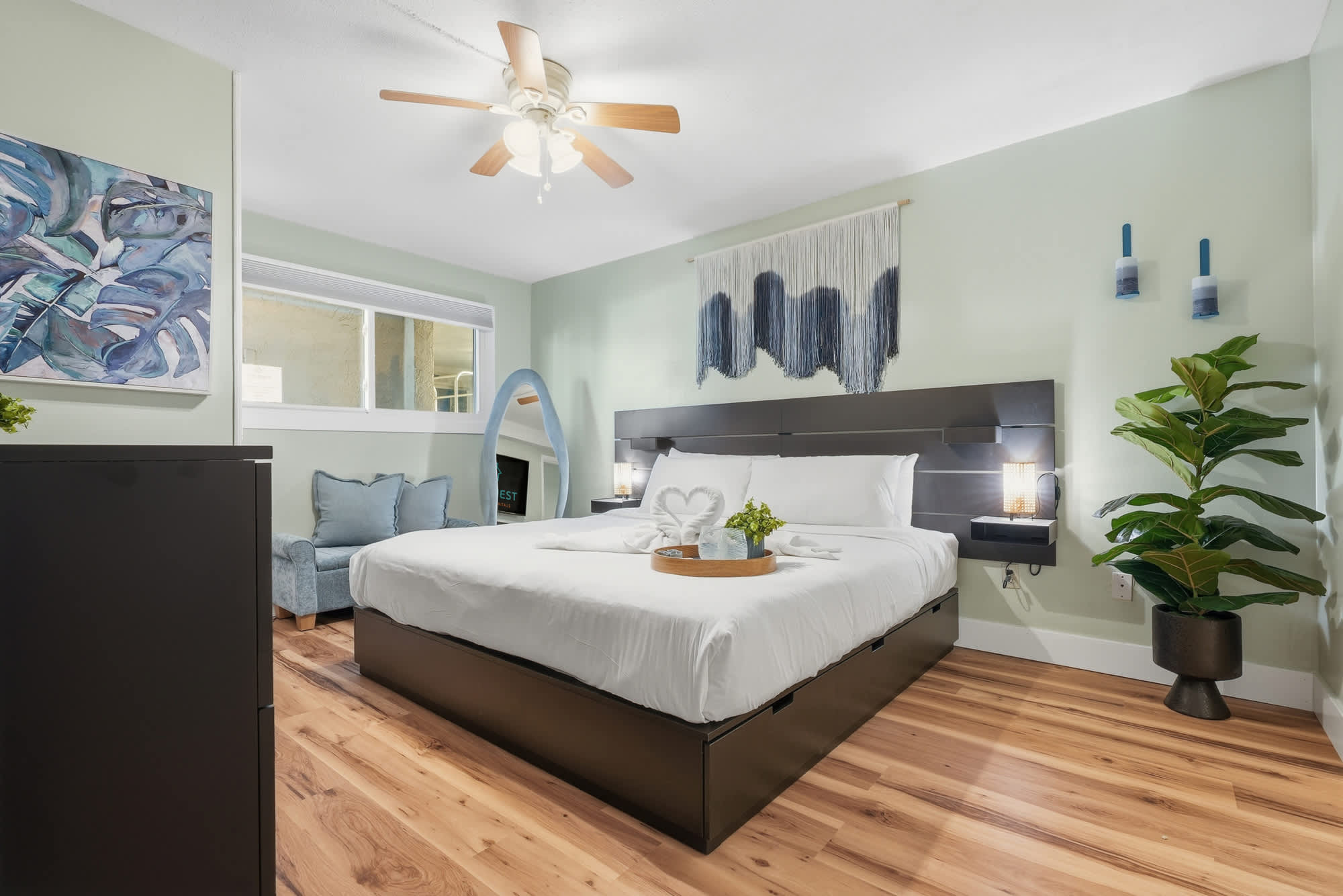 The Summit 131 – Bright bedroom with a king bed, art decor, and potted plant.