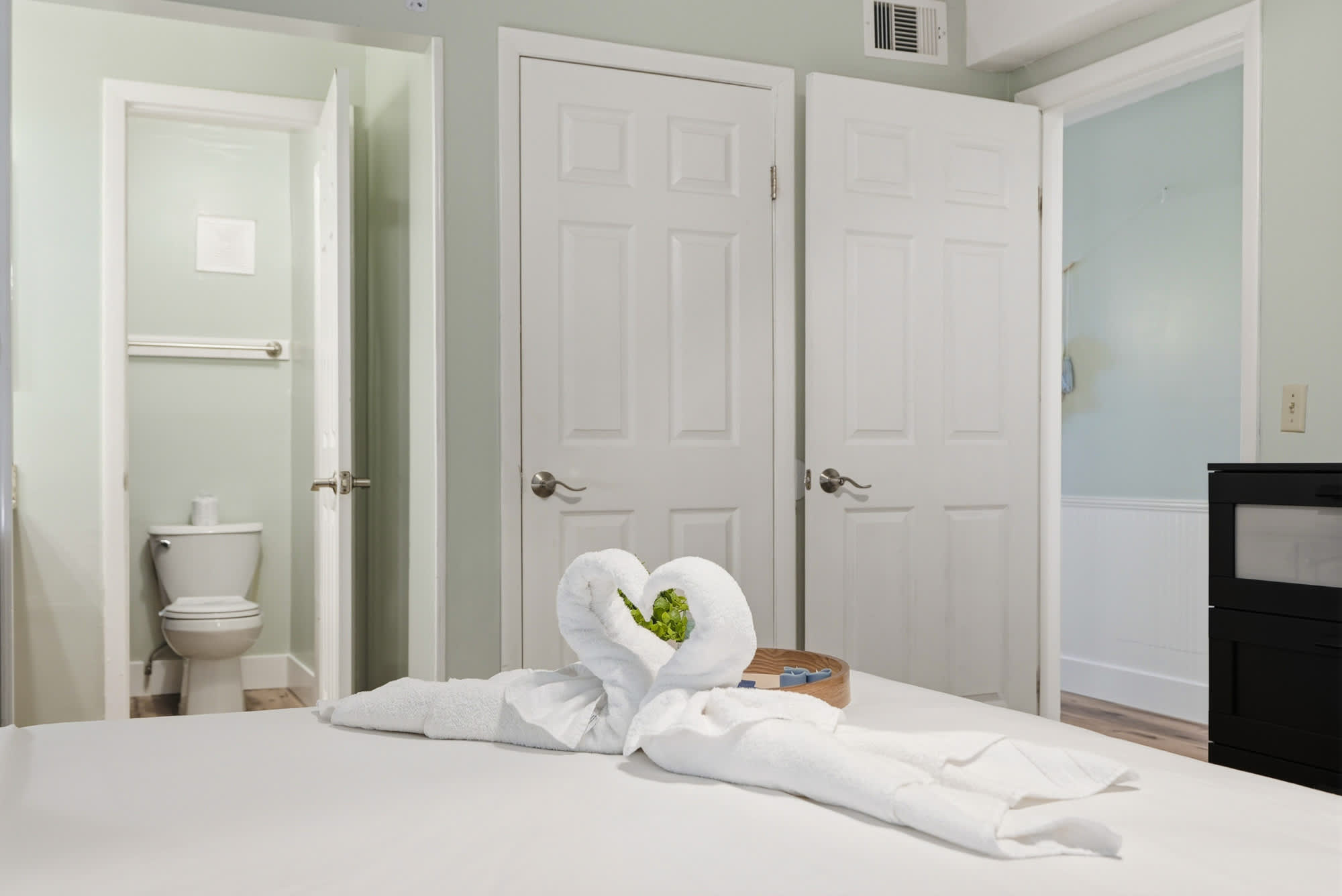 The Summit 131 – Bedroom with towel art on bed, two doors leading to a bathroom and another room.