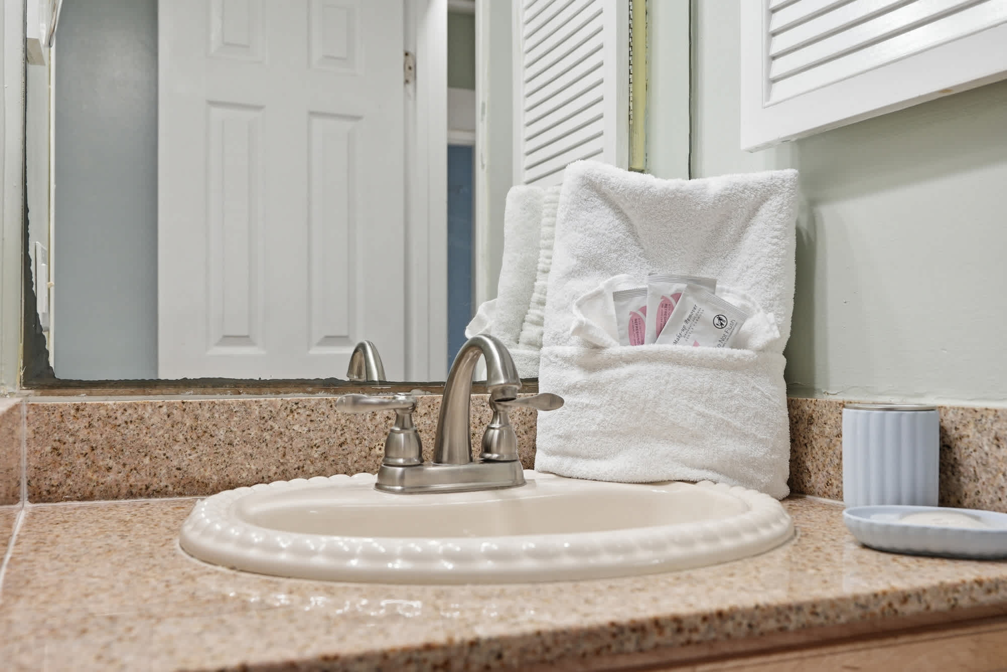 The Summit 131 – Bathroom sink with granitic countertop, mirror, and toiletries in a white towel.