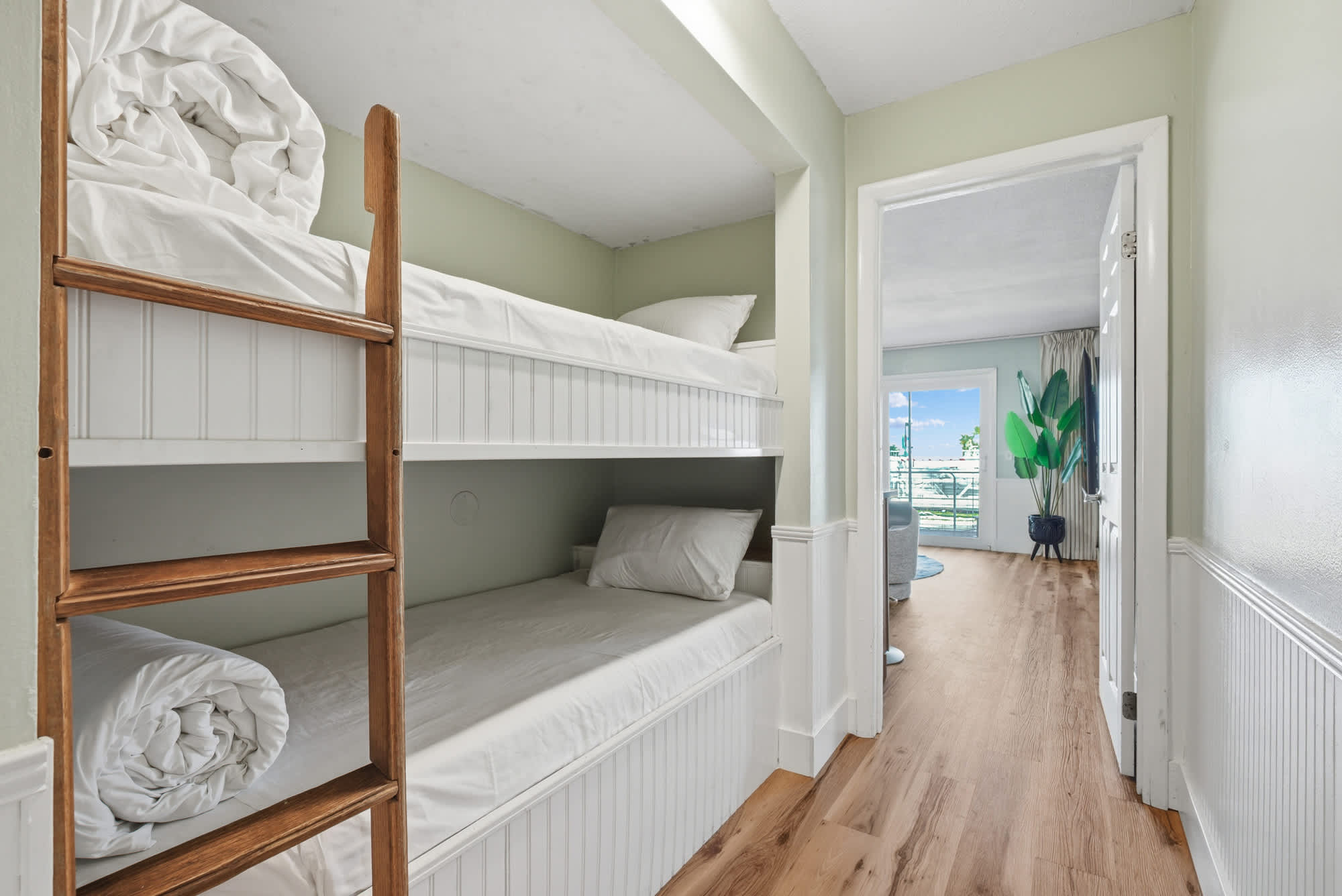 The Summit 131 – Bunk beds with white bedding and views of a living area through an open door.
