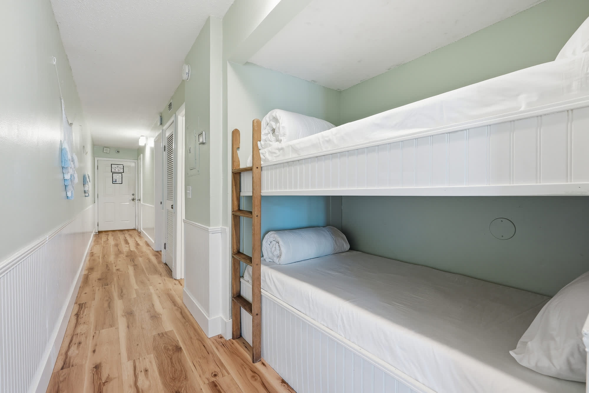 The Summit 131 – Bunk beds in a hallway with light wood flooring and green walls.
