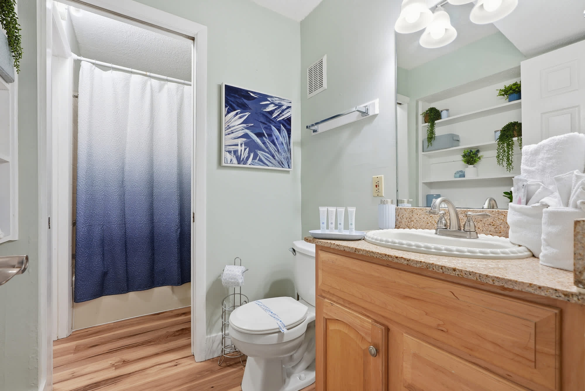 The Summit 131 – Bathroom with a shower, wooden vanity, mirror, and decorative shelves.