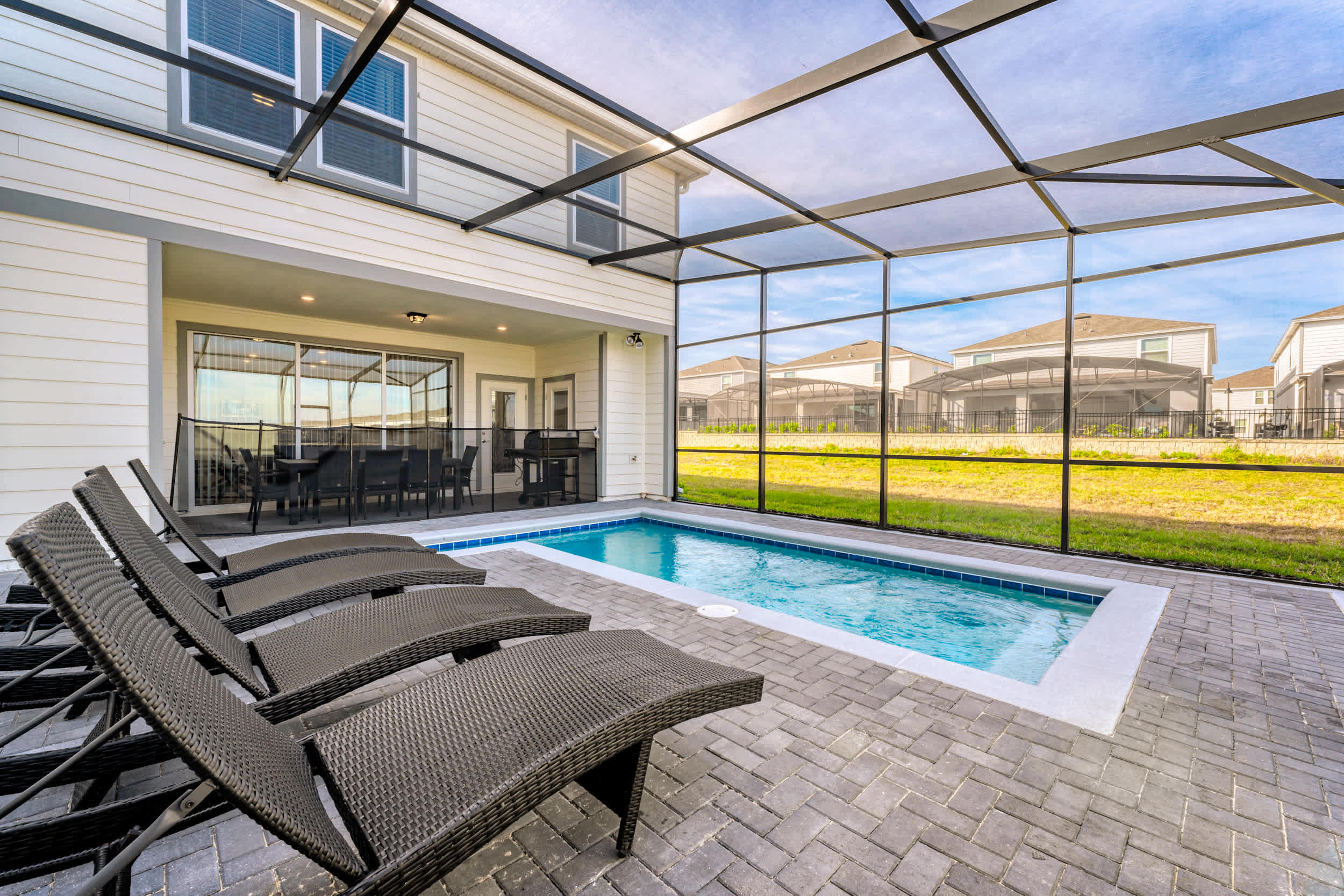 Private screened pool patio with turquoise water, chaise lounges, and a covered outdoor dining area for relaxed days at home.
