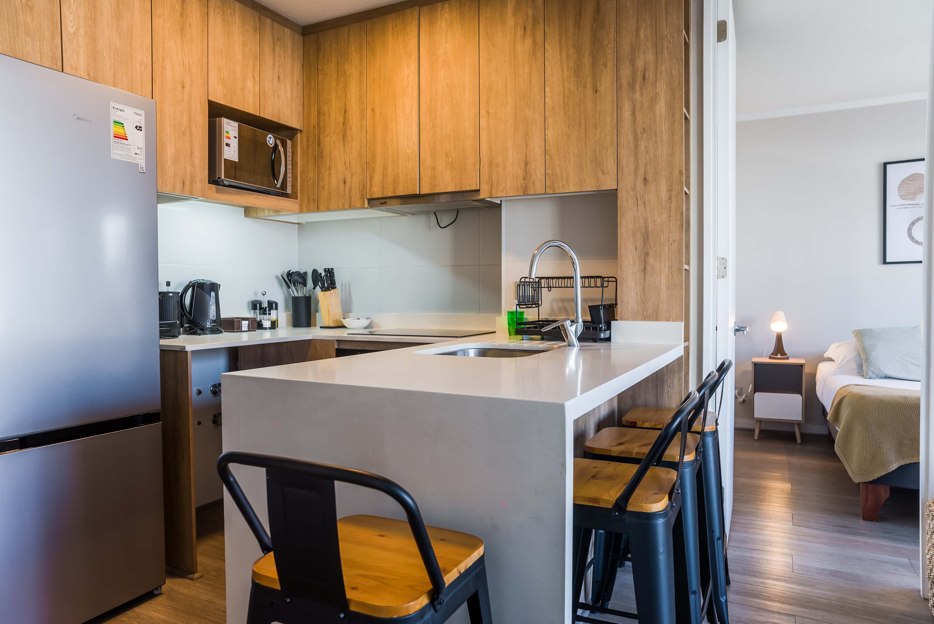 Modern kitchen with sleek wooden cabinetry and cozy bar seating, perfect for a quick meal or morning coffee.