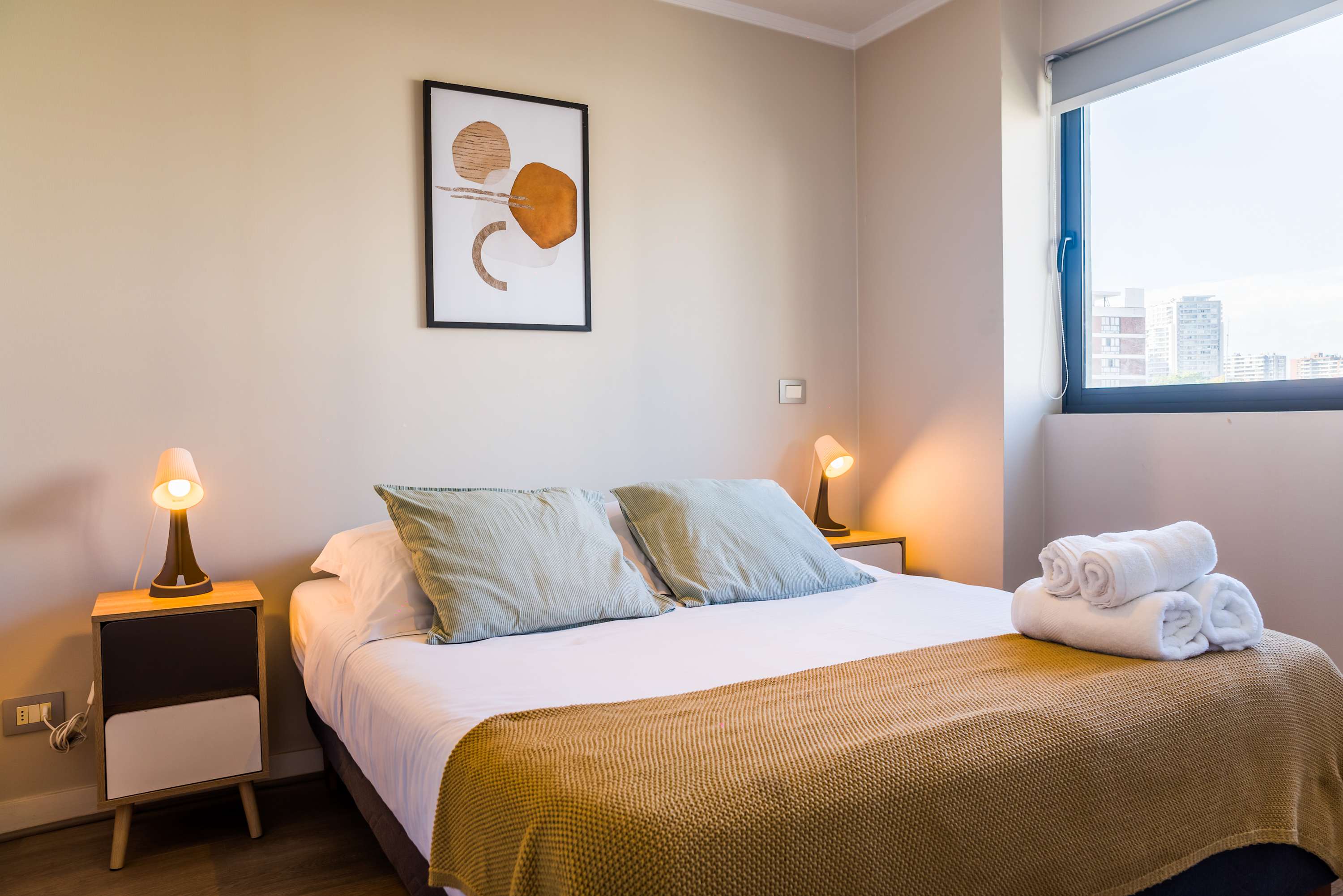 Relax in this cozy bedroom with city views, featuring a plush bed and modern decor.