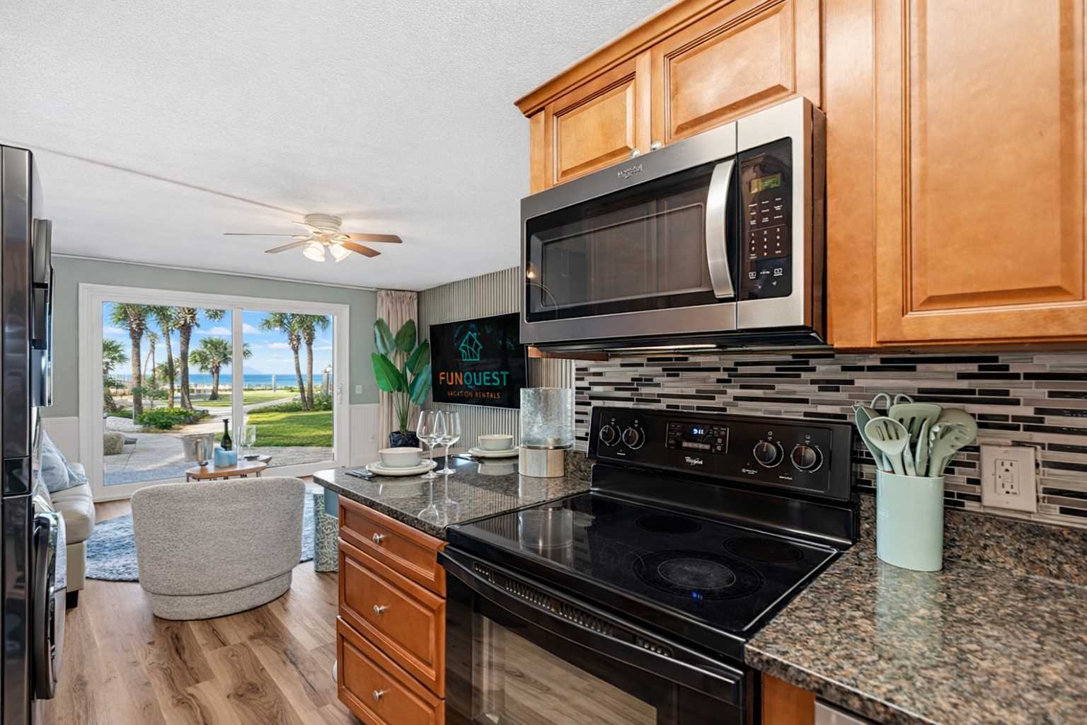 The Summit 131 – Interior view of a kitchen with a stove, microwave, and a seating area overlooking palm trees and the ocean.