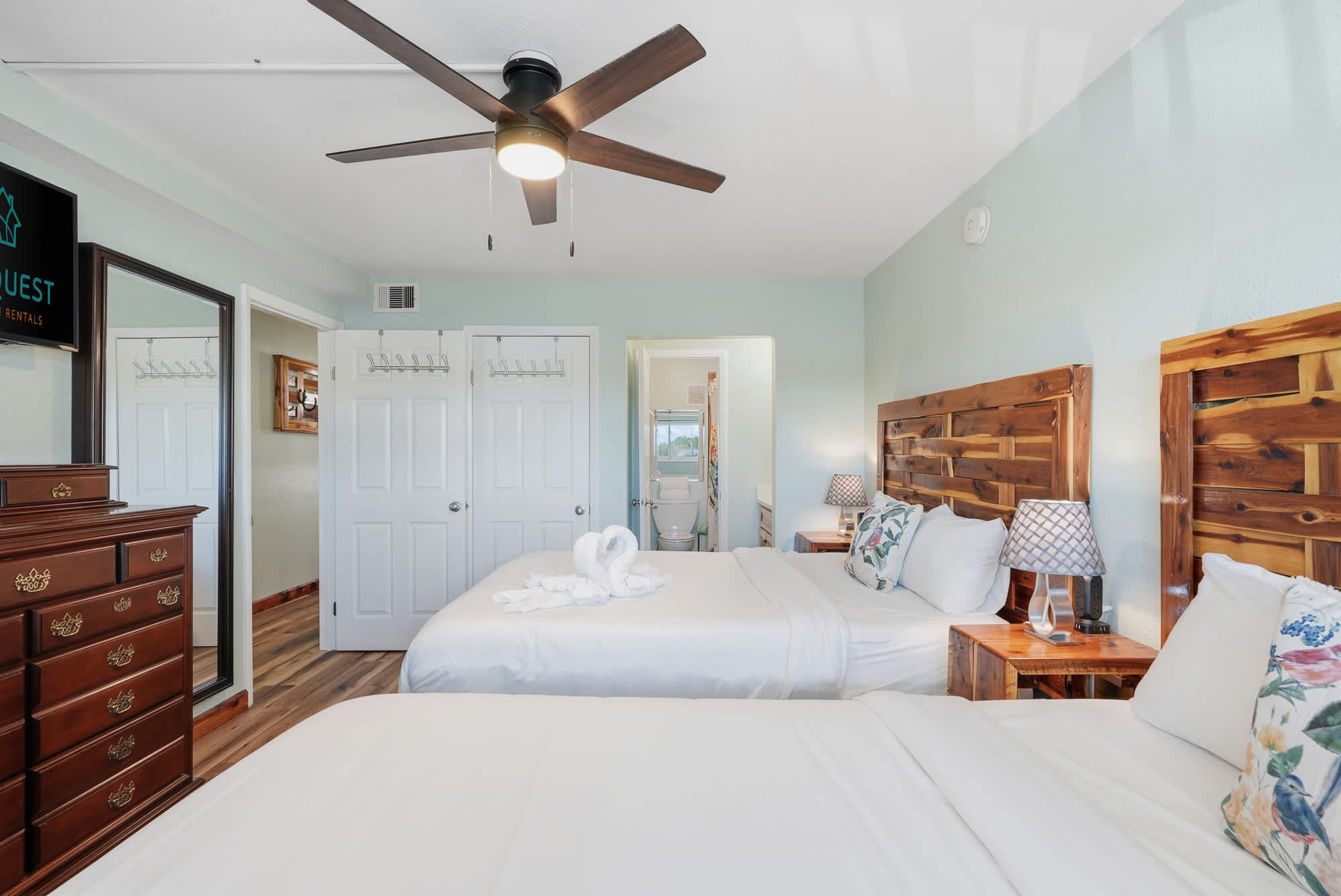 The Summit 206 – Bedroom with two beds, wooden furniture, ceiling fan, and connecting bathroom visible.