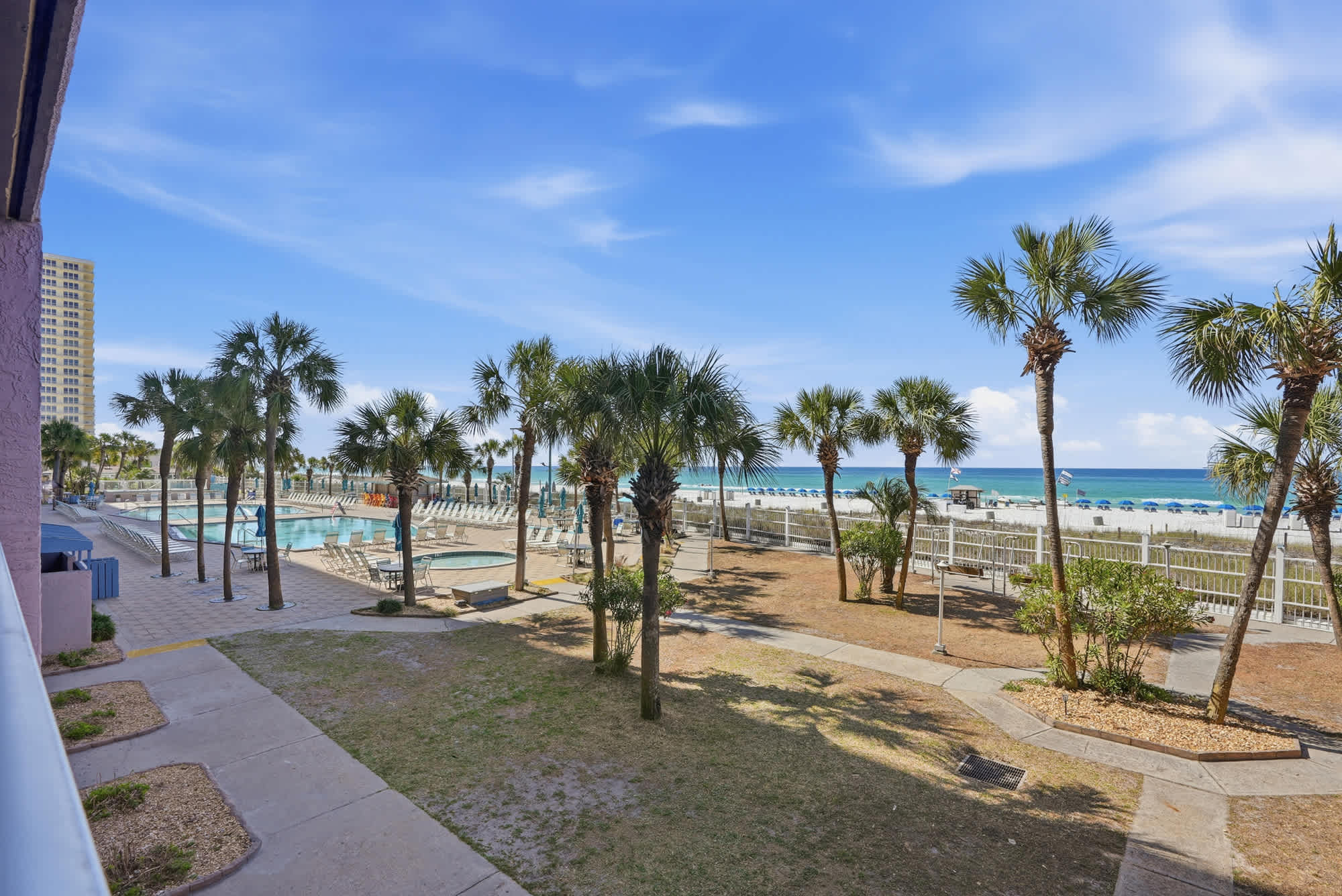 The Summit 206 – View of palm trees, pool area, and beach with ocean in the background from a balcony.