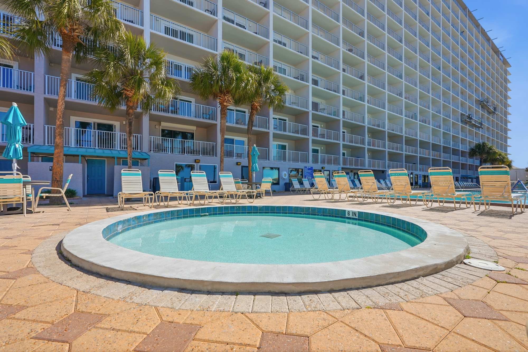The Summit 206 – Pool area with hot tub, lounge chairs, and a multi-story building in the background.