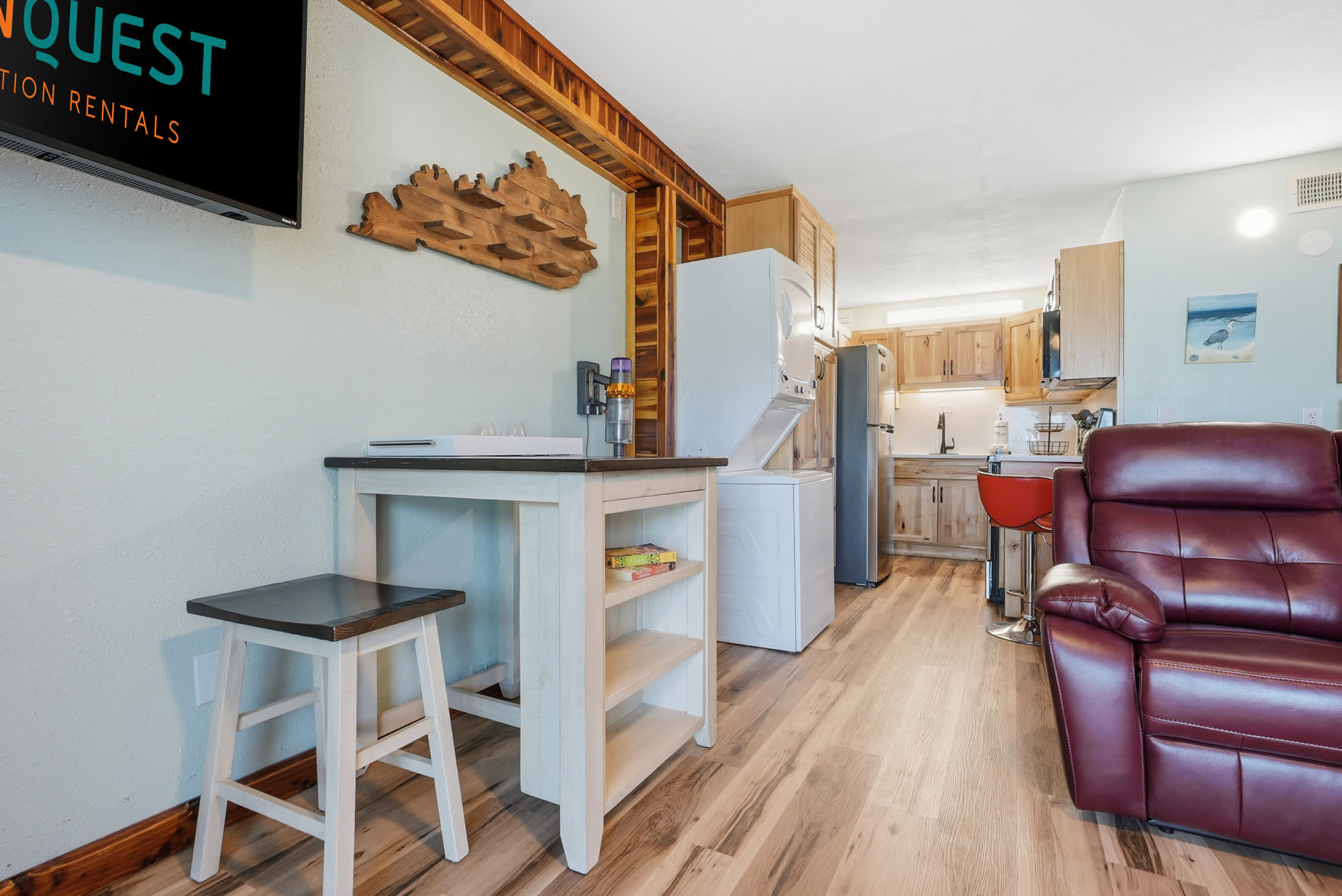 The Summit 206 – Cozy studio with kitchenette, red leather chair, wooden accents, and laundry appliances.