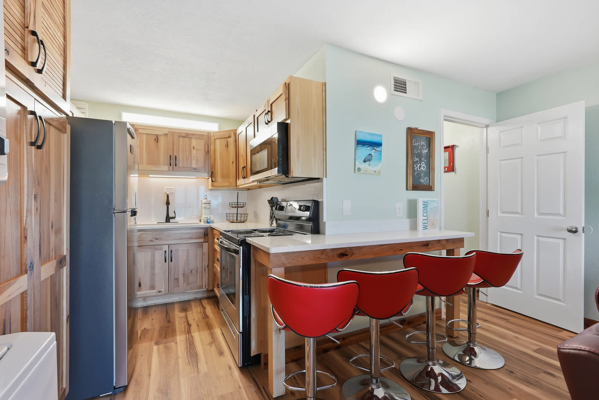 The Summit 206 – Kitchen with wooden cabinets, stainless steel appliances, and red bar stools at a counter.