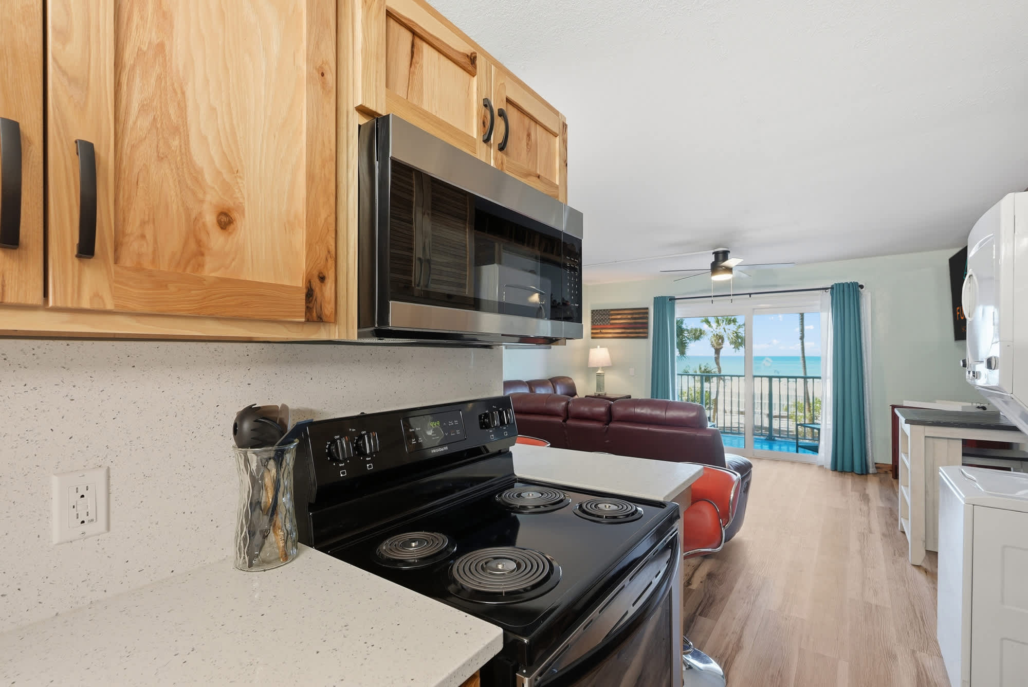 The Summit 206 – Cozy kitchen with black appliances, living area, and ocean view through large sliding glass doors.