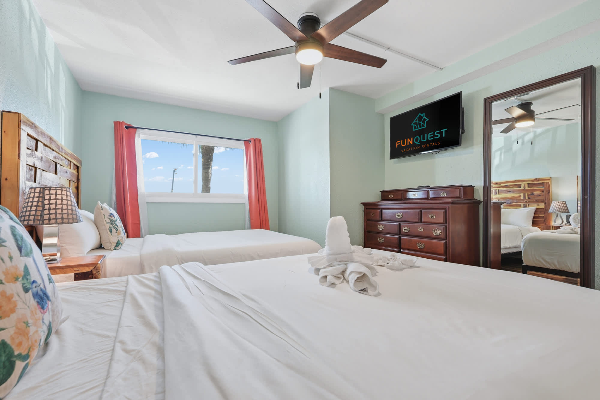 The Summit 206 – Bedroom with two beds, a dresser, TV, and window with palm tree view.