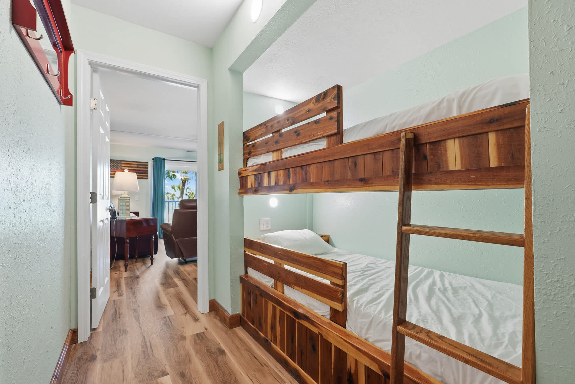The Summit 206 – Bunk beds in a hallway with a view of a living area and balcony beyond.