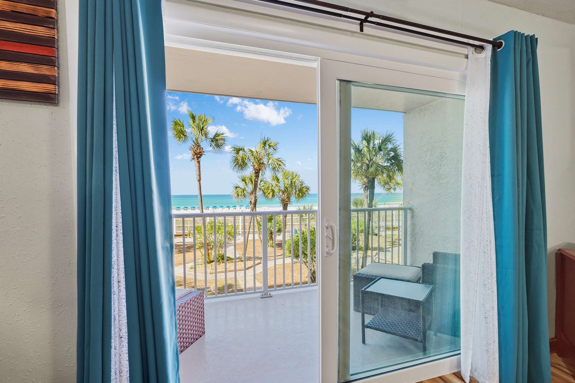 The Summit 206 – View from balcony with palm trees and ocean in the background, featuring a small seating area.
