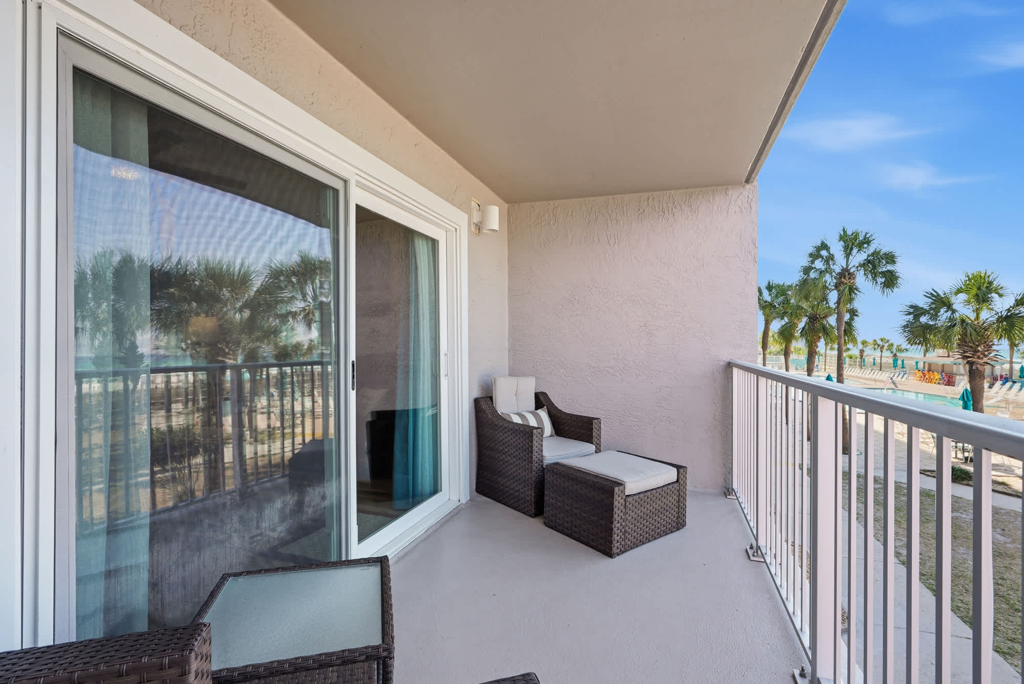The Summit 206 – Balcony with rattan seating and palm tree view, overlooking the pool area.