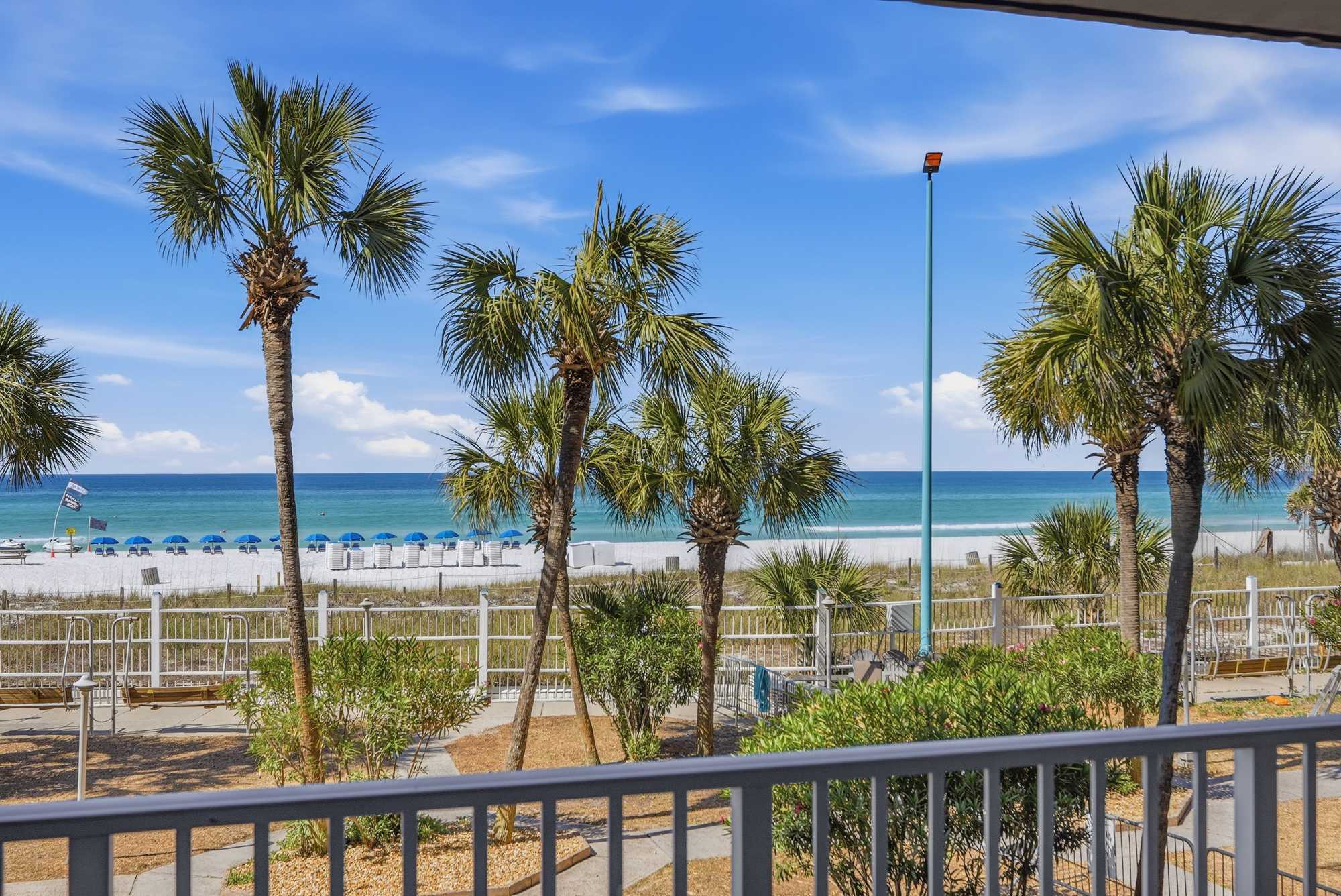 The Summit 206 – View of beach with palm trees, umbrellas, and ocean in the background.