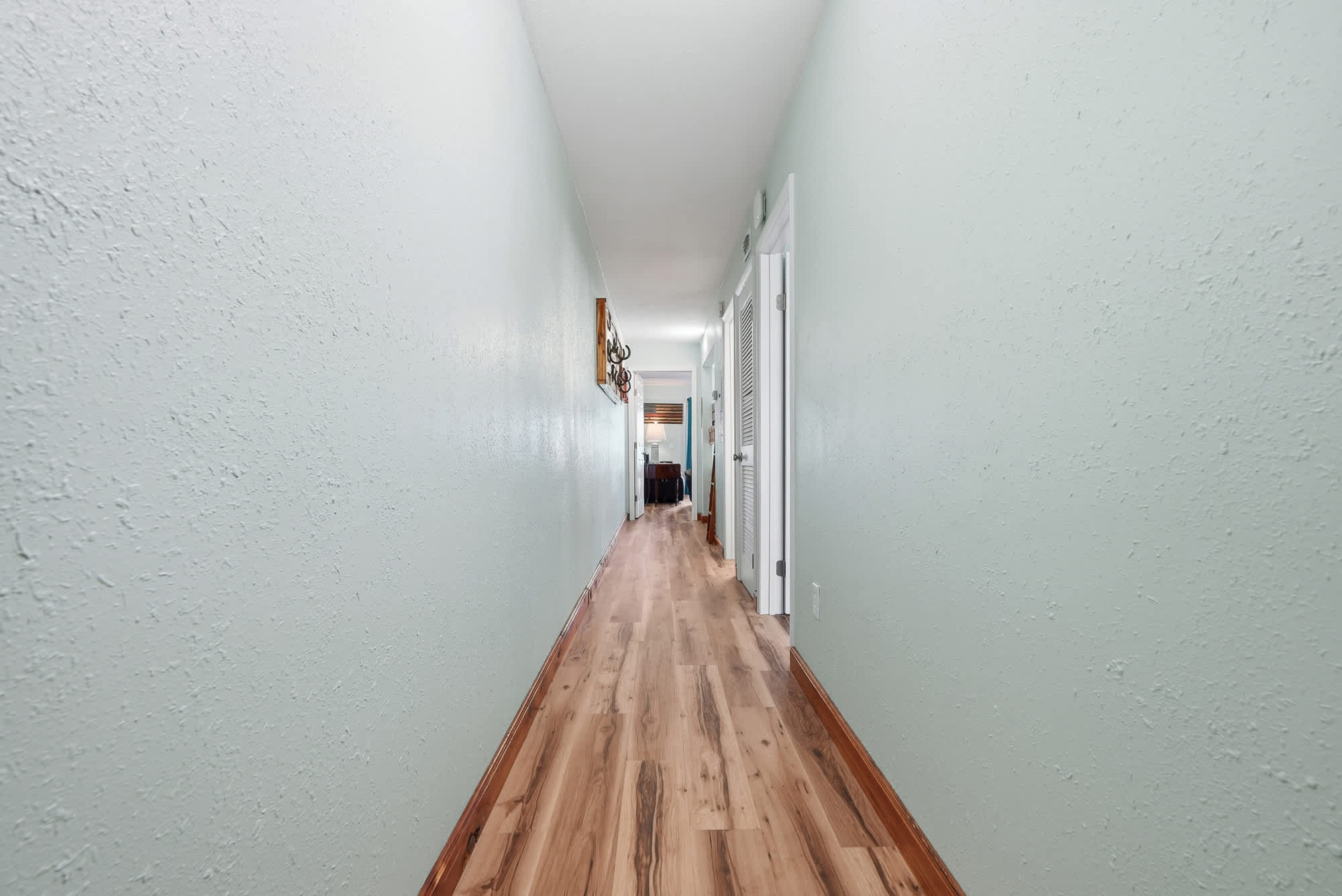 The Summit 206 – Narrow hallway with light green walls and wooden flooring, leading to a living area.