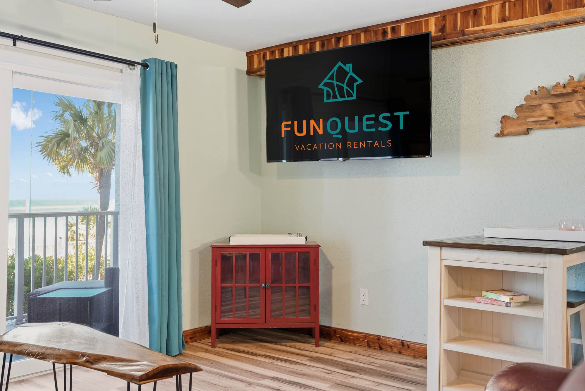 The Summit 206 – Living room with a TV, red cabinet, and ocean view through a sliding glass door.