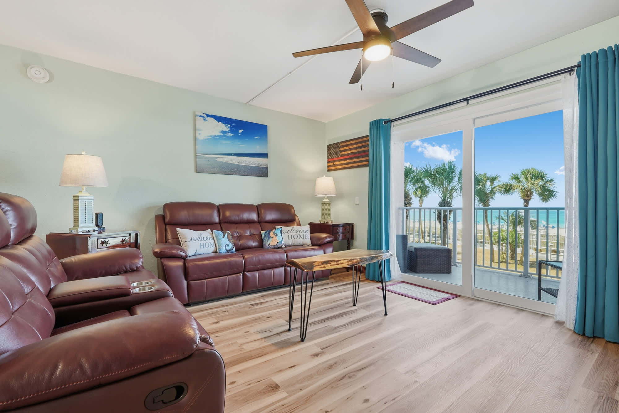 The Summit 206 – Living room with leather sofas, wooden coffee table, balcony view of palm trees and ocean.