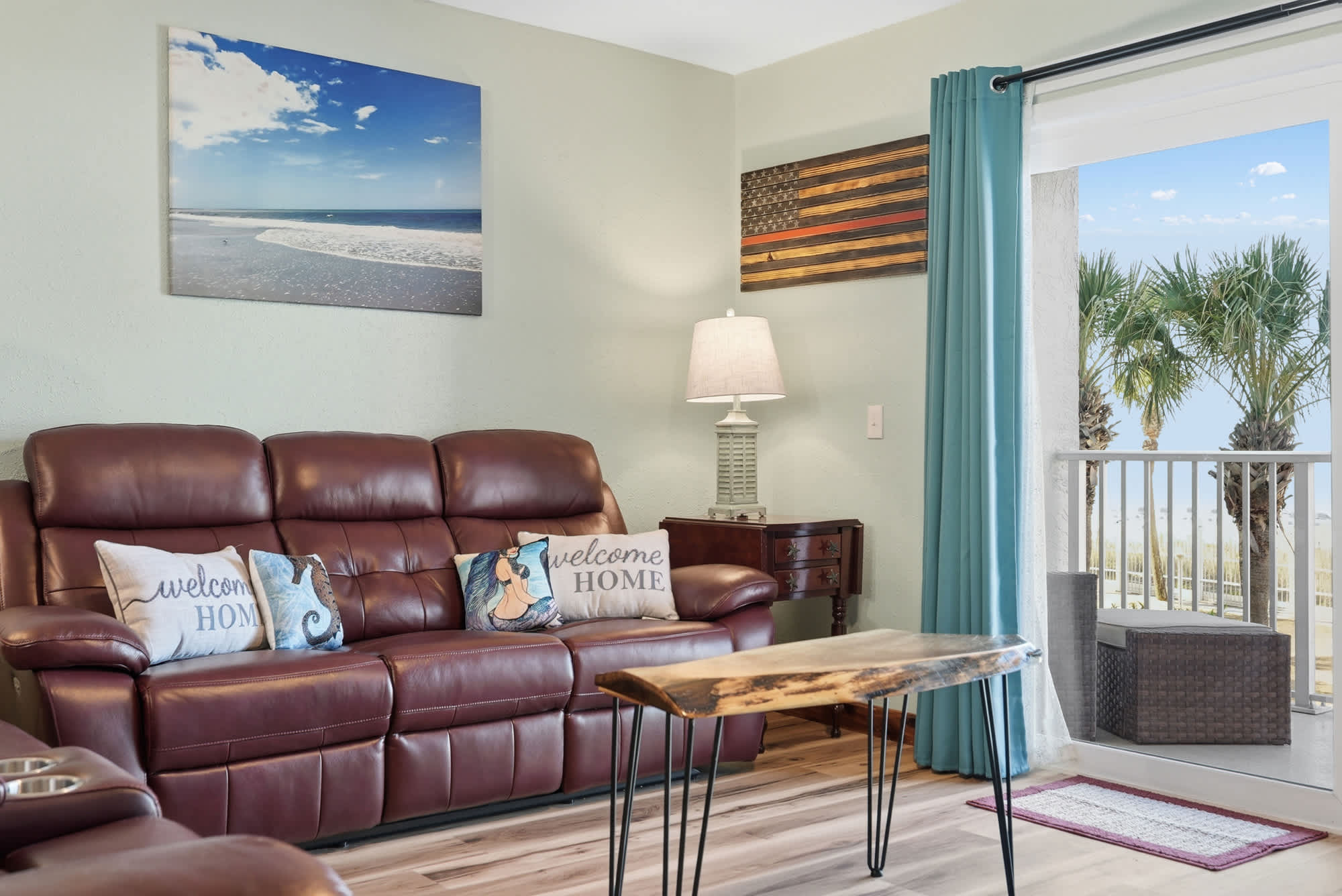 The Summit 206 – Living room with brown leather couch, decorative pillows, lamp, and balcony view of palm trees.