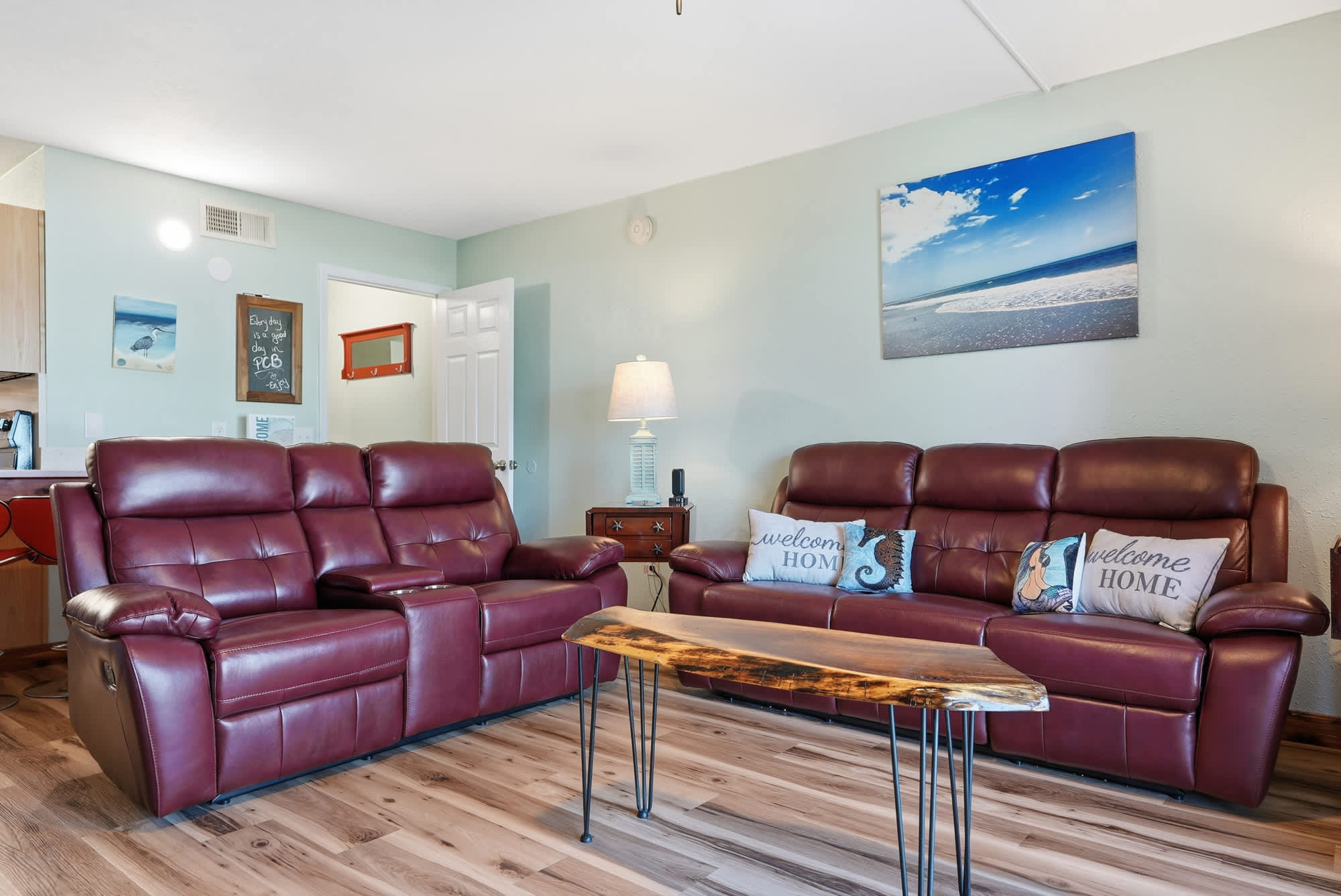 The Summit 206 – Living room with brown reclining sofas, wooden coffee table, and beach-themed wall art.