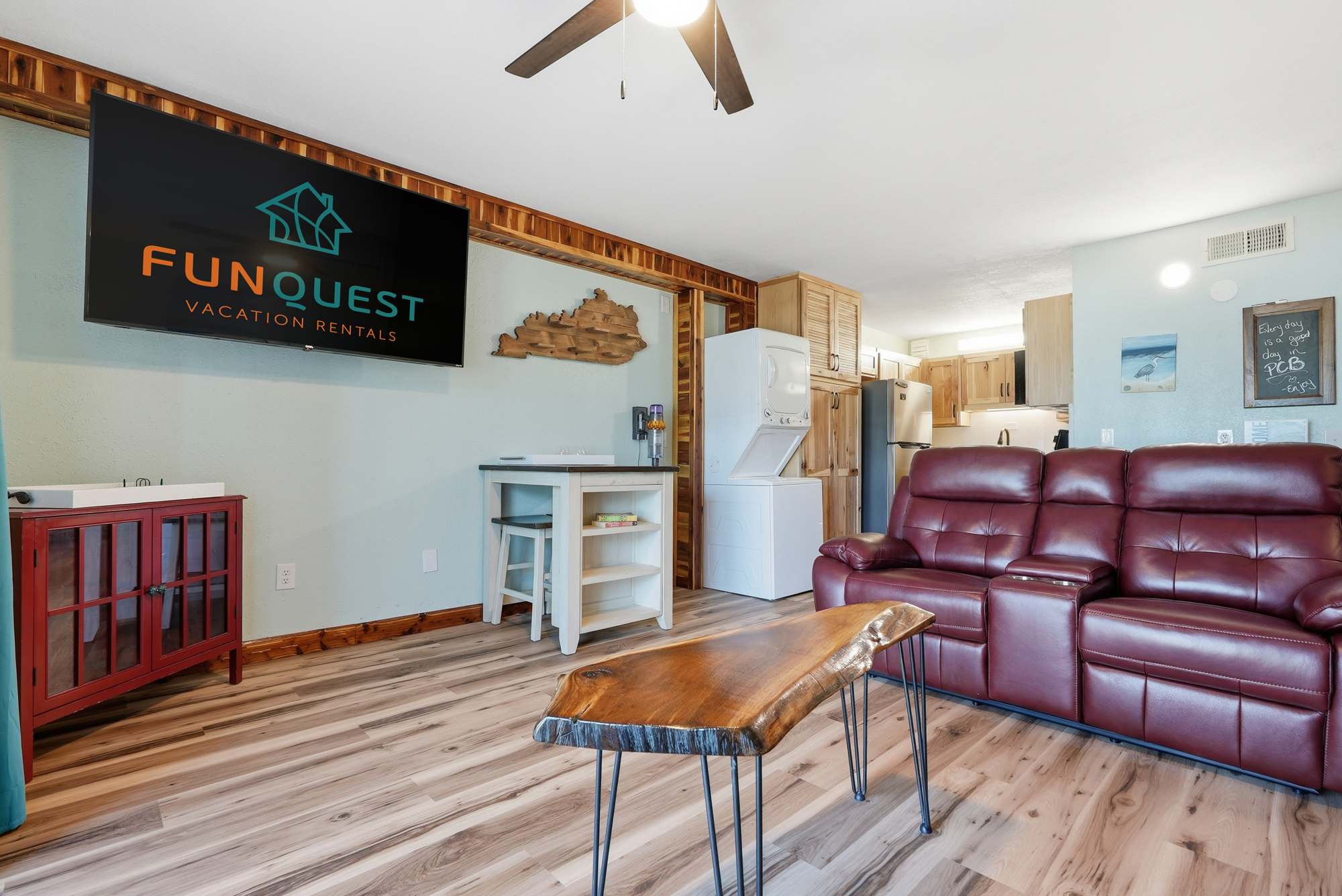 The Summit 206 – Living room with red recliners, wooden coffee table, television, and kitchenette in the background.
