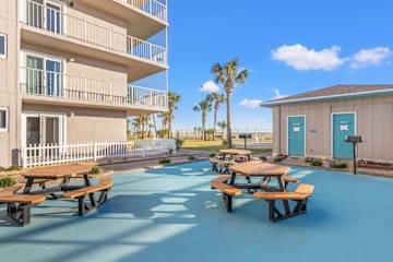 The Summit 626 – Exterior view of The Summit 626 with picnic tables, palm trees, and nearby beach access.