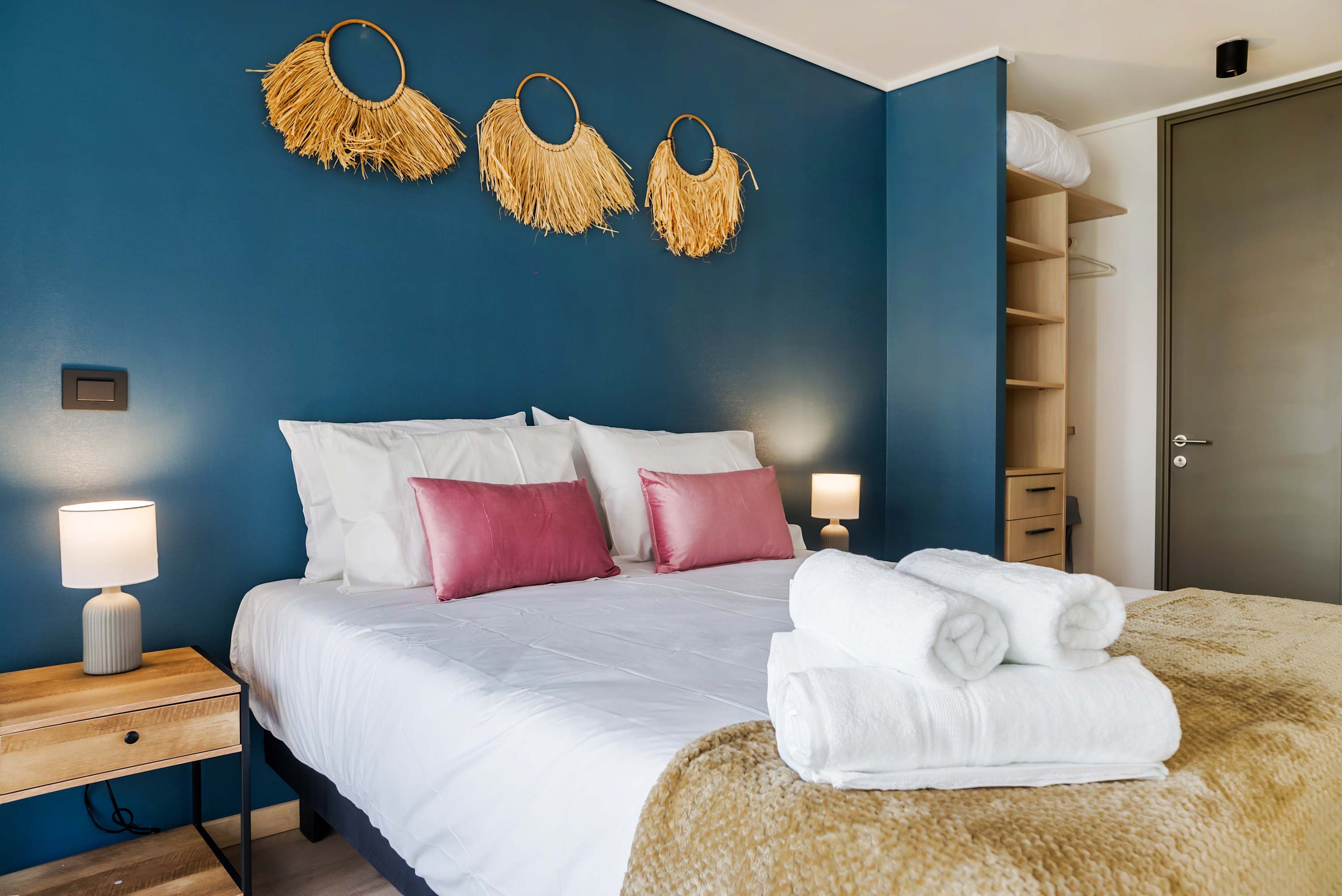 Relax in this stylish bedroom with a vibrant blue accent wall and plush bedding, perfect for a restful stay.