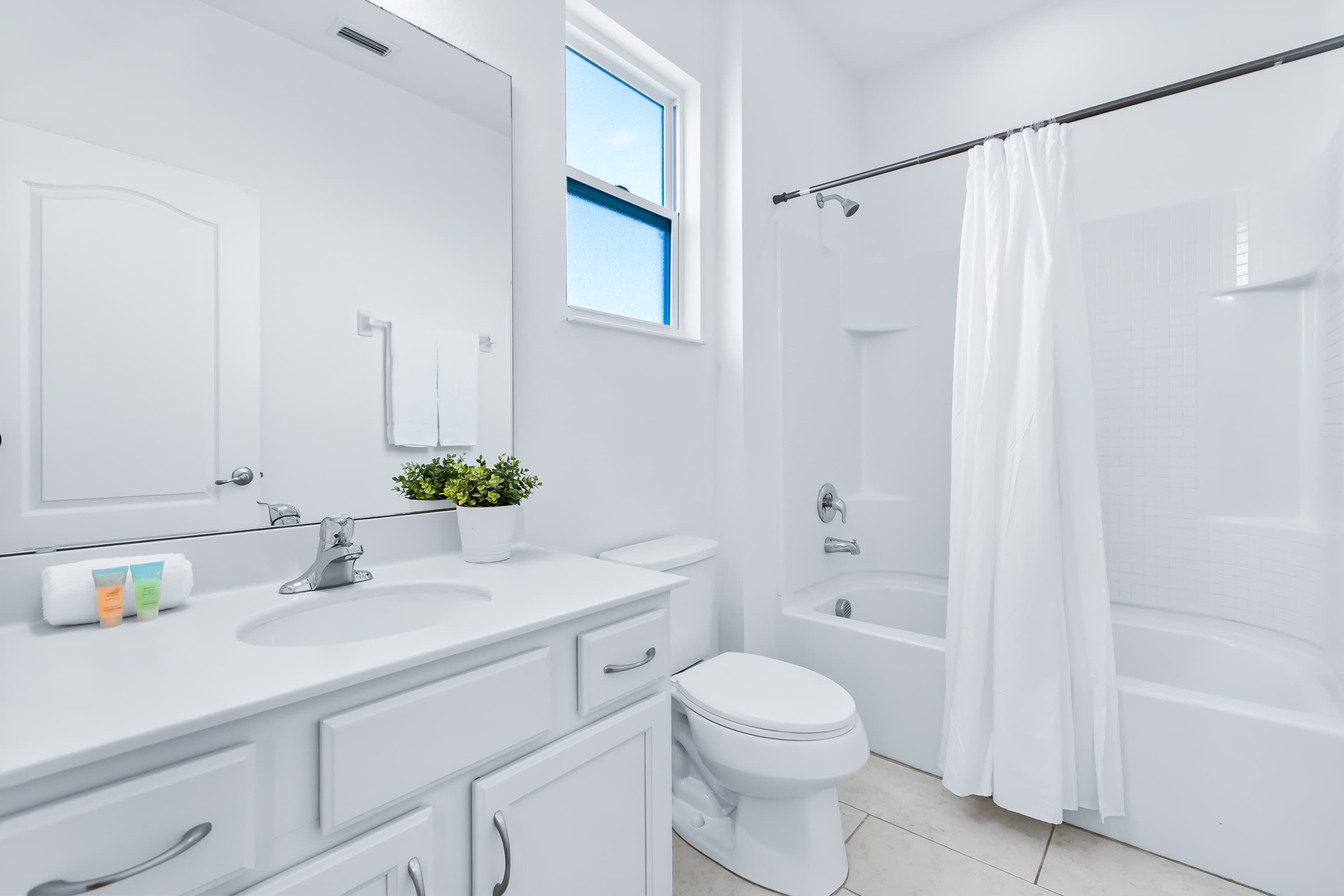 Bright bathroom with shower/tub combo and modern finishes.