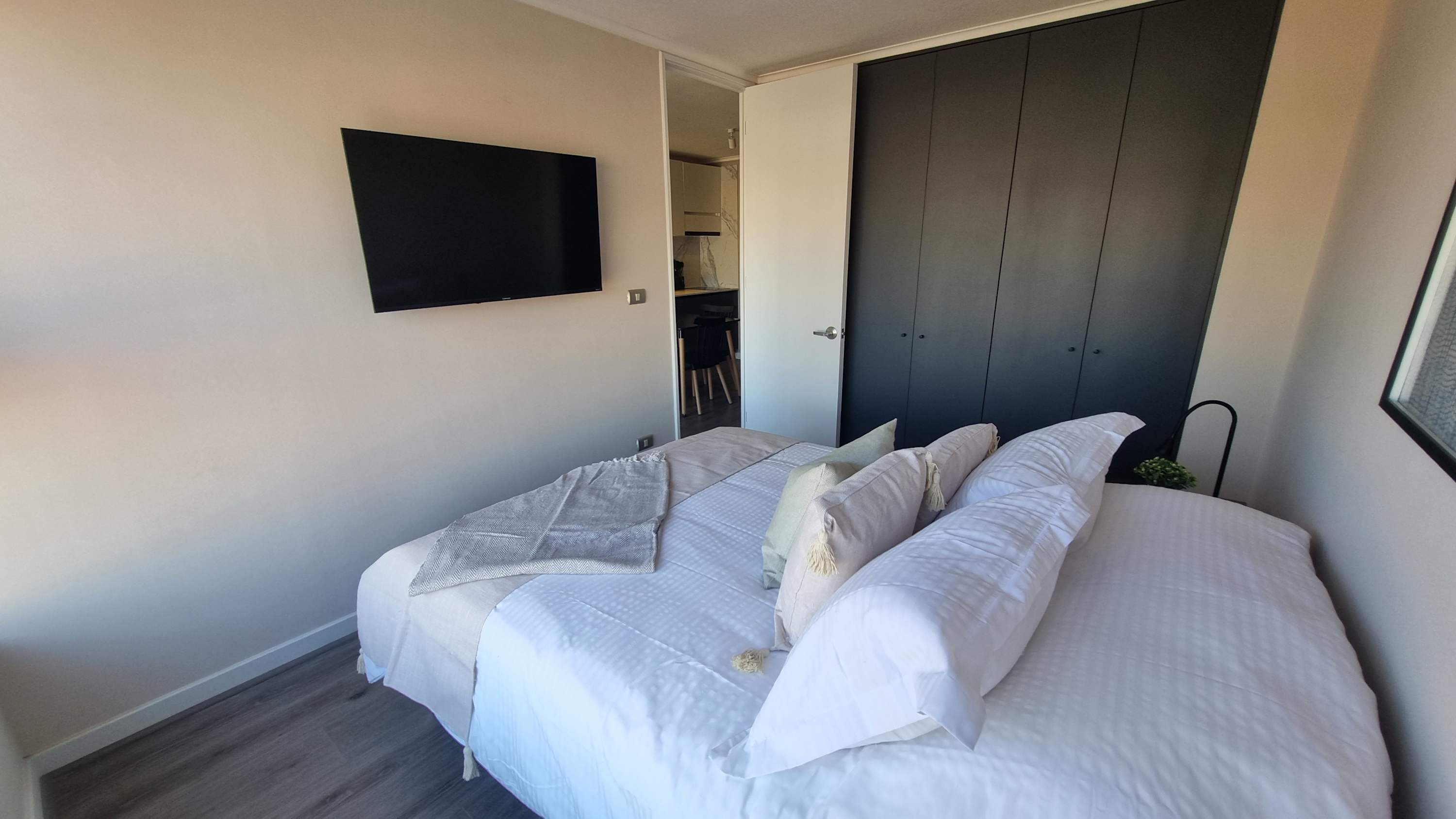 Cozy bedroom with modern amenities and a sleek TV, perfect for relaxation in the heart of the city.